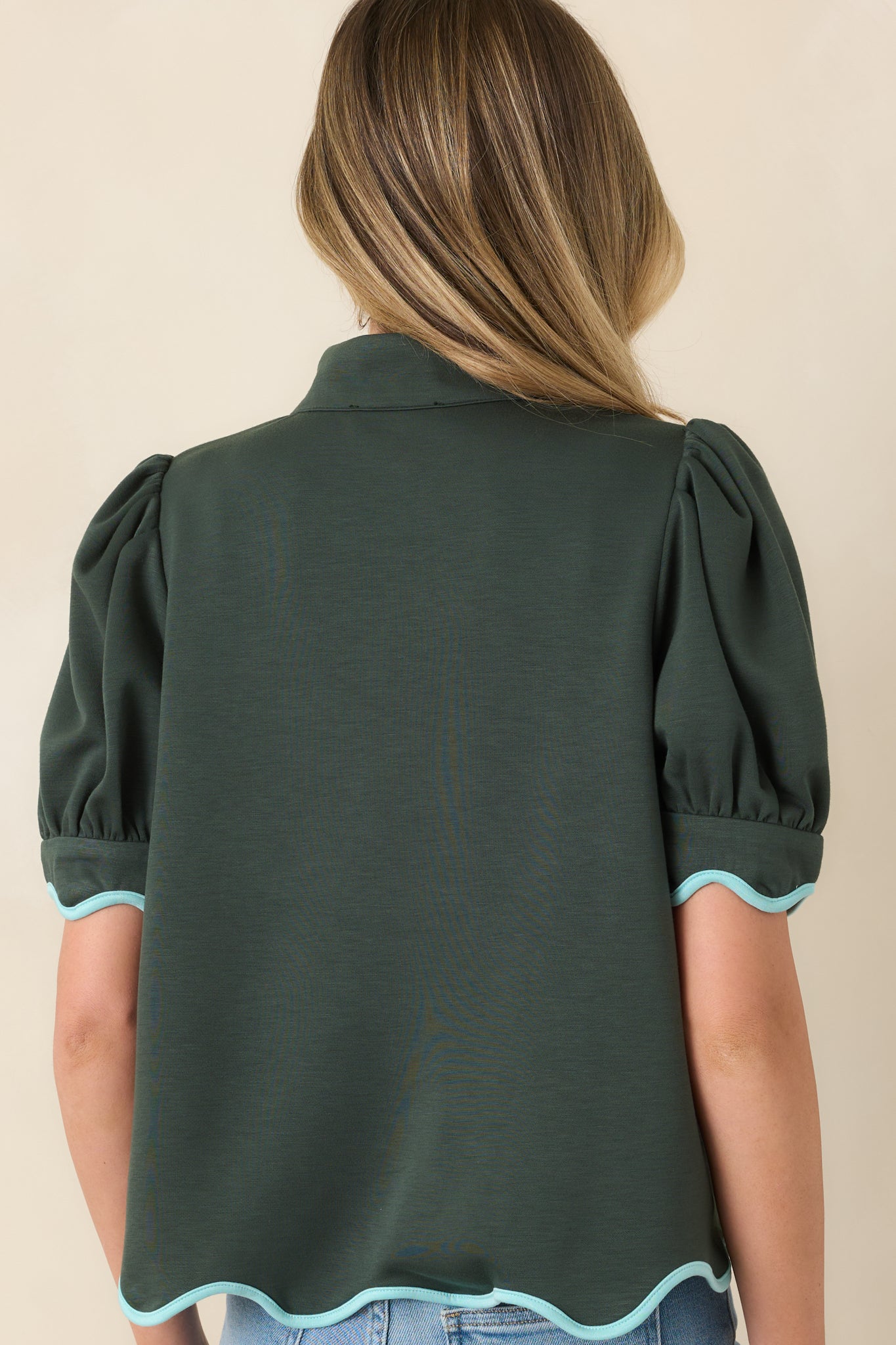 Rear view of the hunter green knit top showcasing the relaxed shape and scalloped hem.