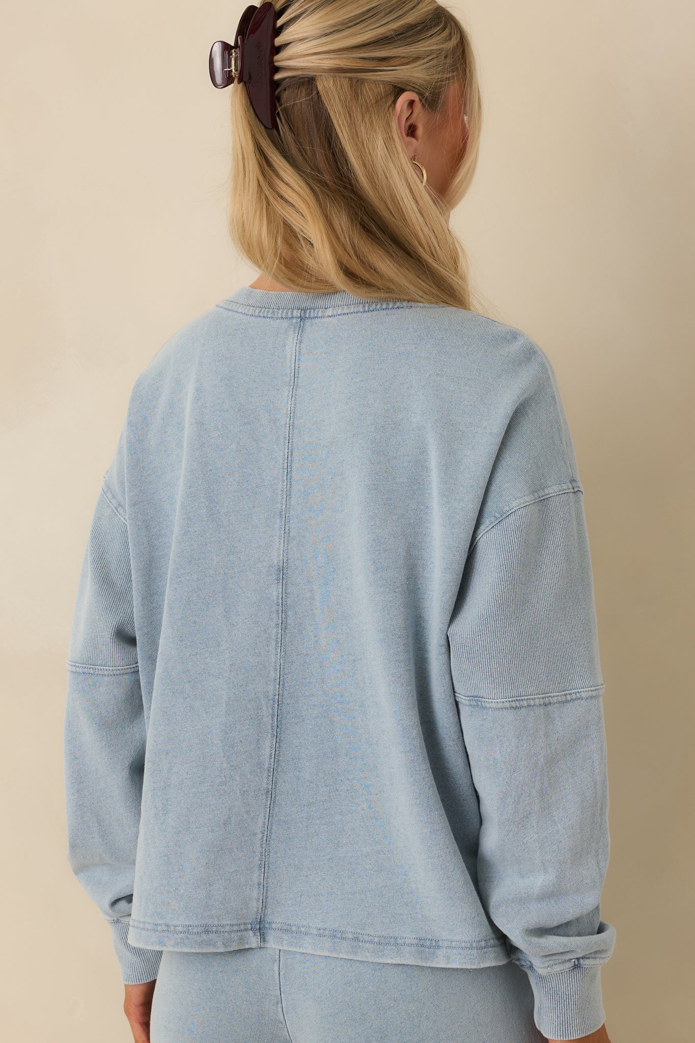 Rear view of the indigo sweatshirt showing the relaxed silhouette, long sleeves, and ribbed hem and cuffs.