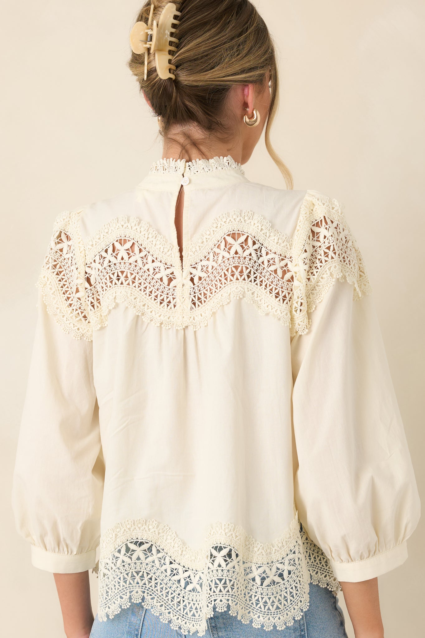 Rear view of the ivory blouse showcasing the keyhole button closure and lace-trimmed hem.