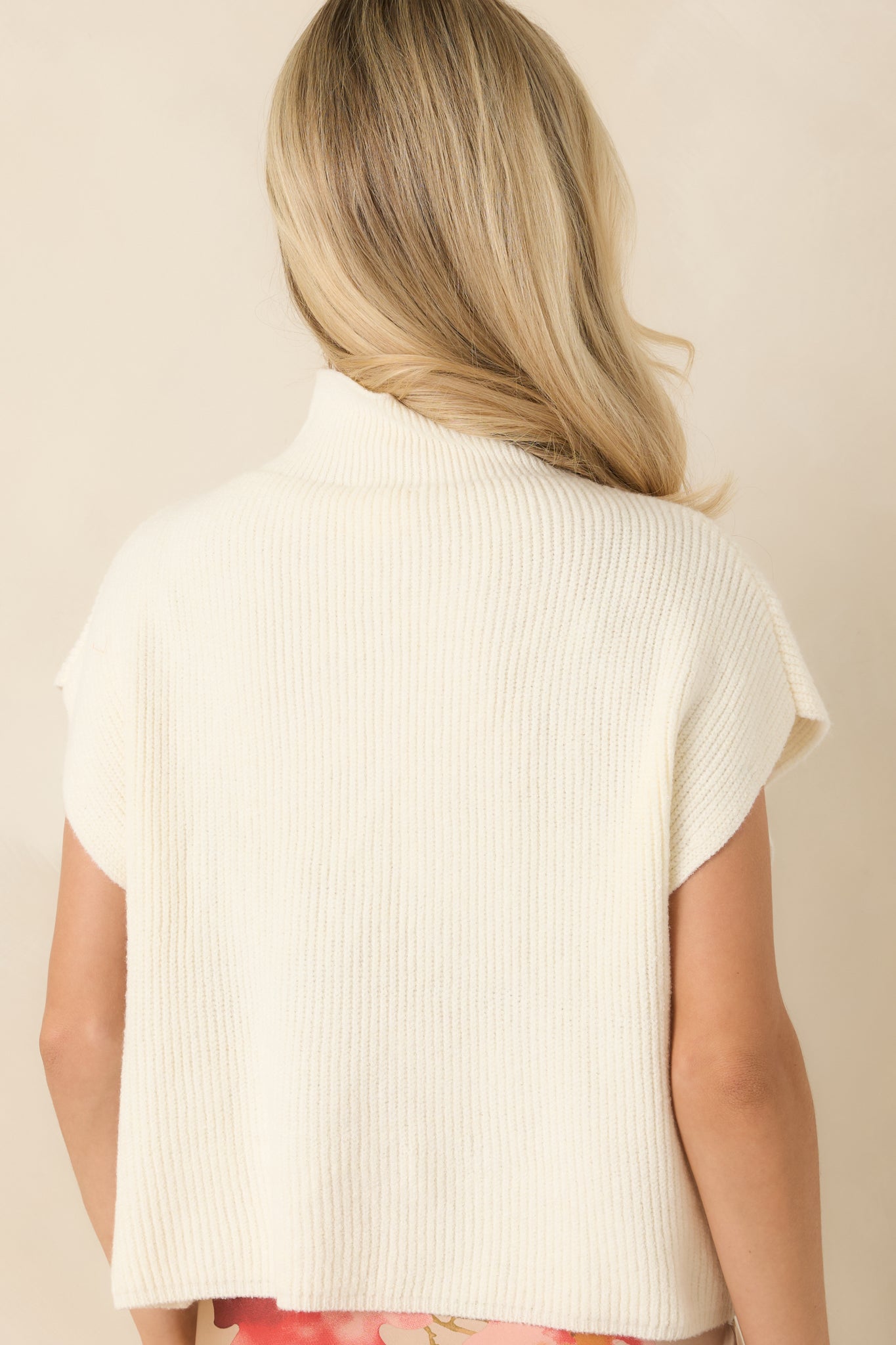 Rear view of the ivory ribbed knit sweater highlighting the smooth silhouette, cap sleeves, and clean hemline.