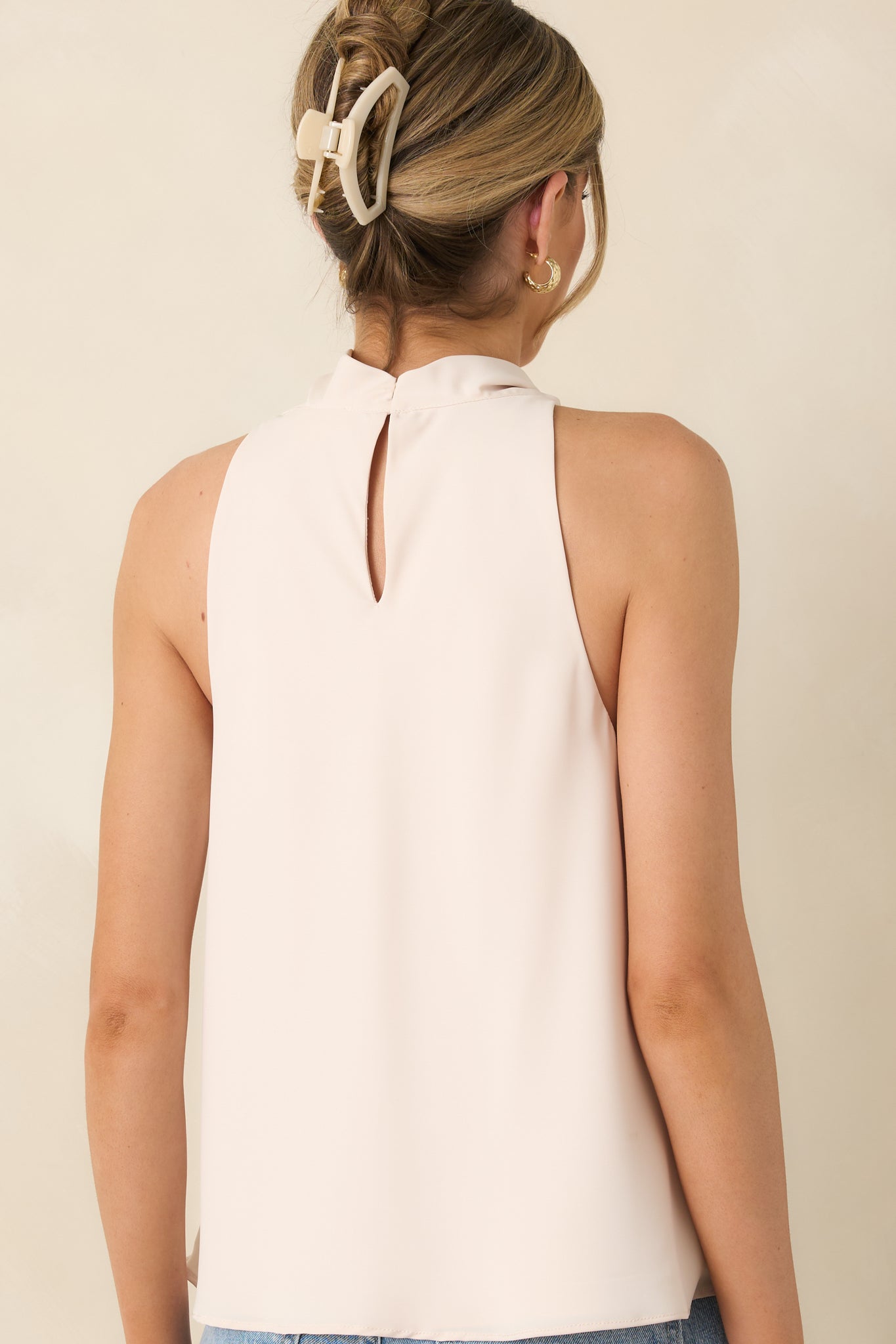 Rear view of light beige top with sleeveless cut and relaxed silhouette.
