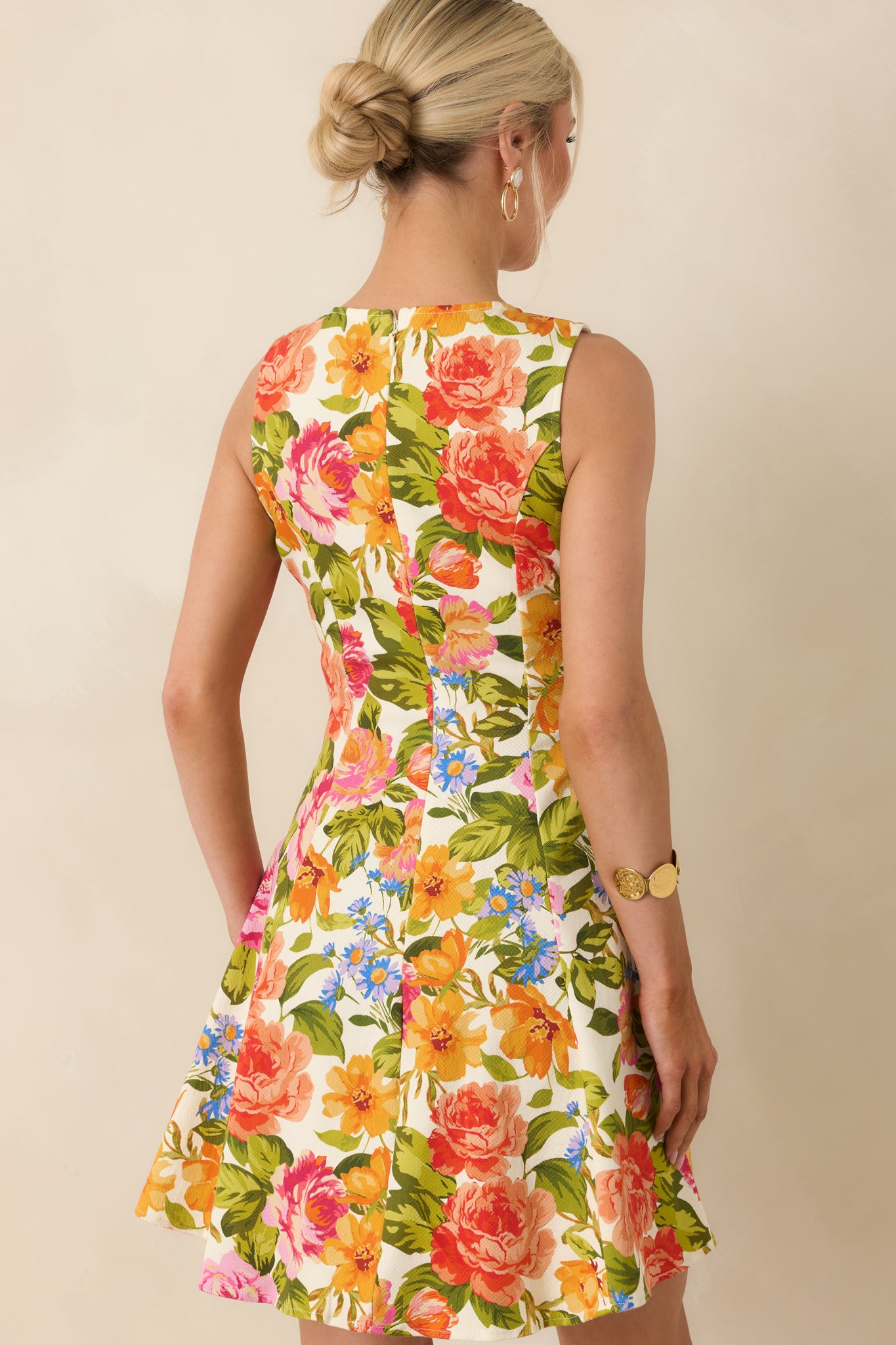Rear view of ivory mini dress with multi floral print, sleeveless cut, and flared skirt silhouette