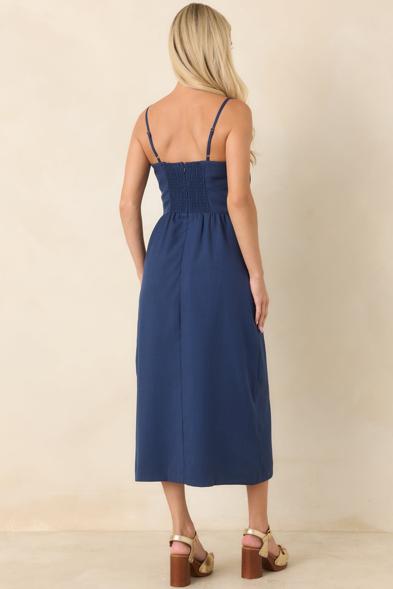 Rear view of the navy midi dress showcasing the smocked back panel and softly flowing skirt.