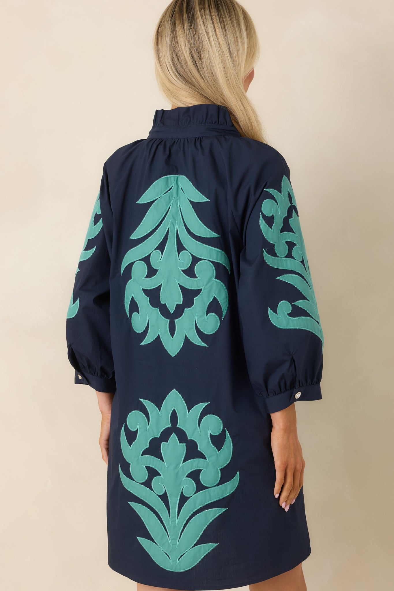 Rear view of navy mini dress with three-quarter sleeves and clean, lightweight finish.