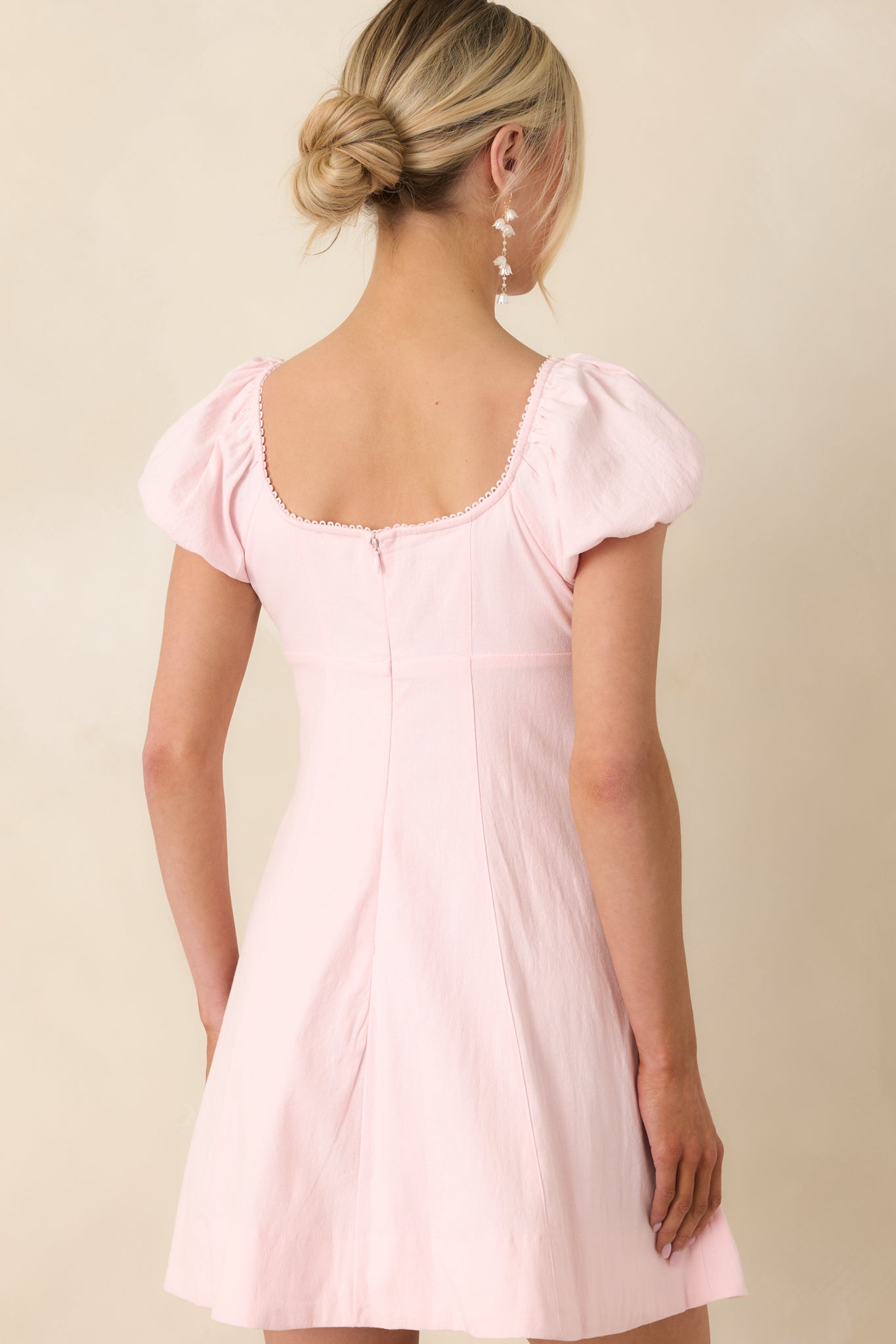 Rear view of peony pink cotton mini dress with puff sleeves and flared skirt.


