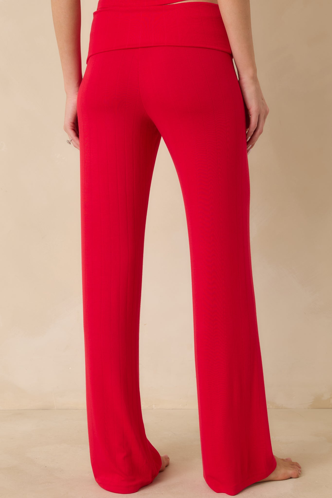 Rear view of red fold-over pants showing the relaxed fit and wide leg opening