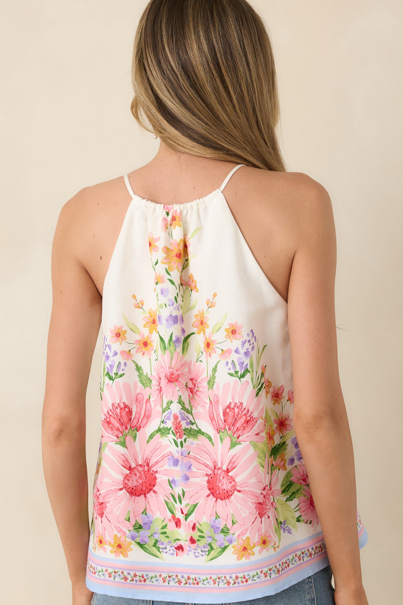 Rear view of ivory multi floral halter top with relaxed drape.