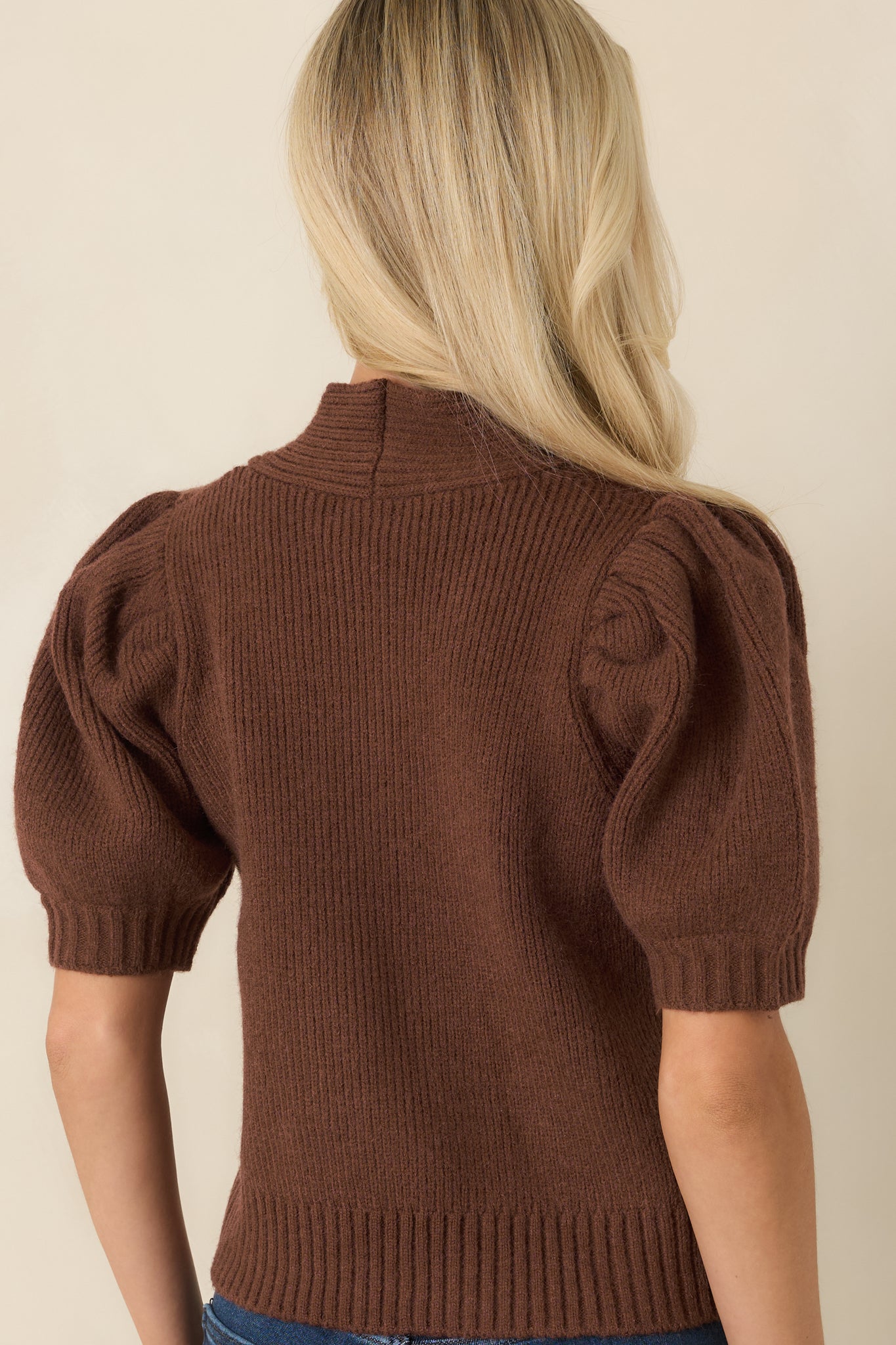 Rear view of the ribbed knit top showcasing the fitted silhouette, puff sleeves, and structured ribbed hem.