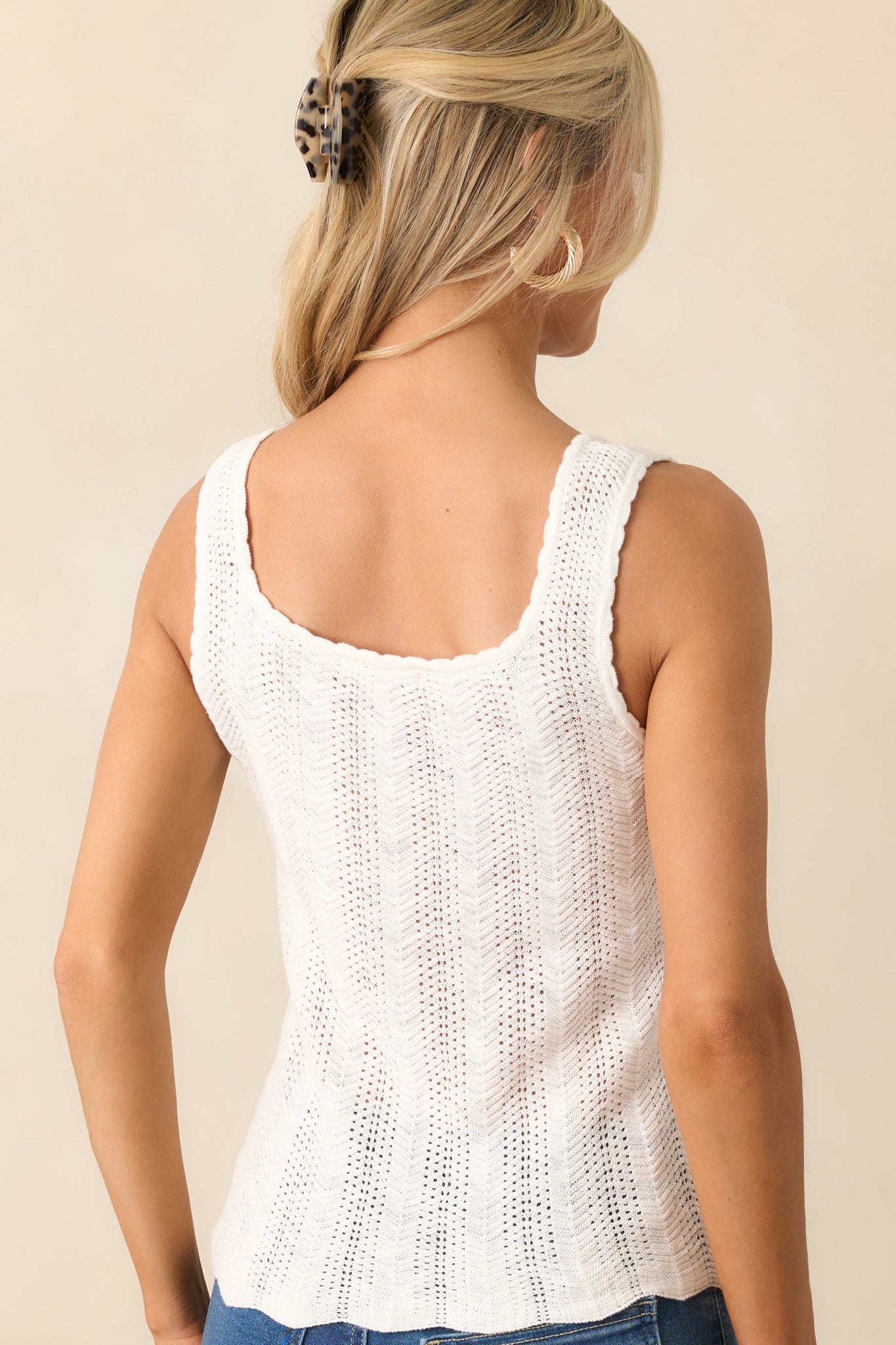 Rear view of sleeveless white top showing the open knit design and continuation of scalloped hems.