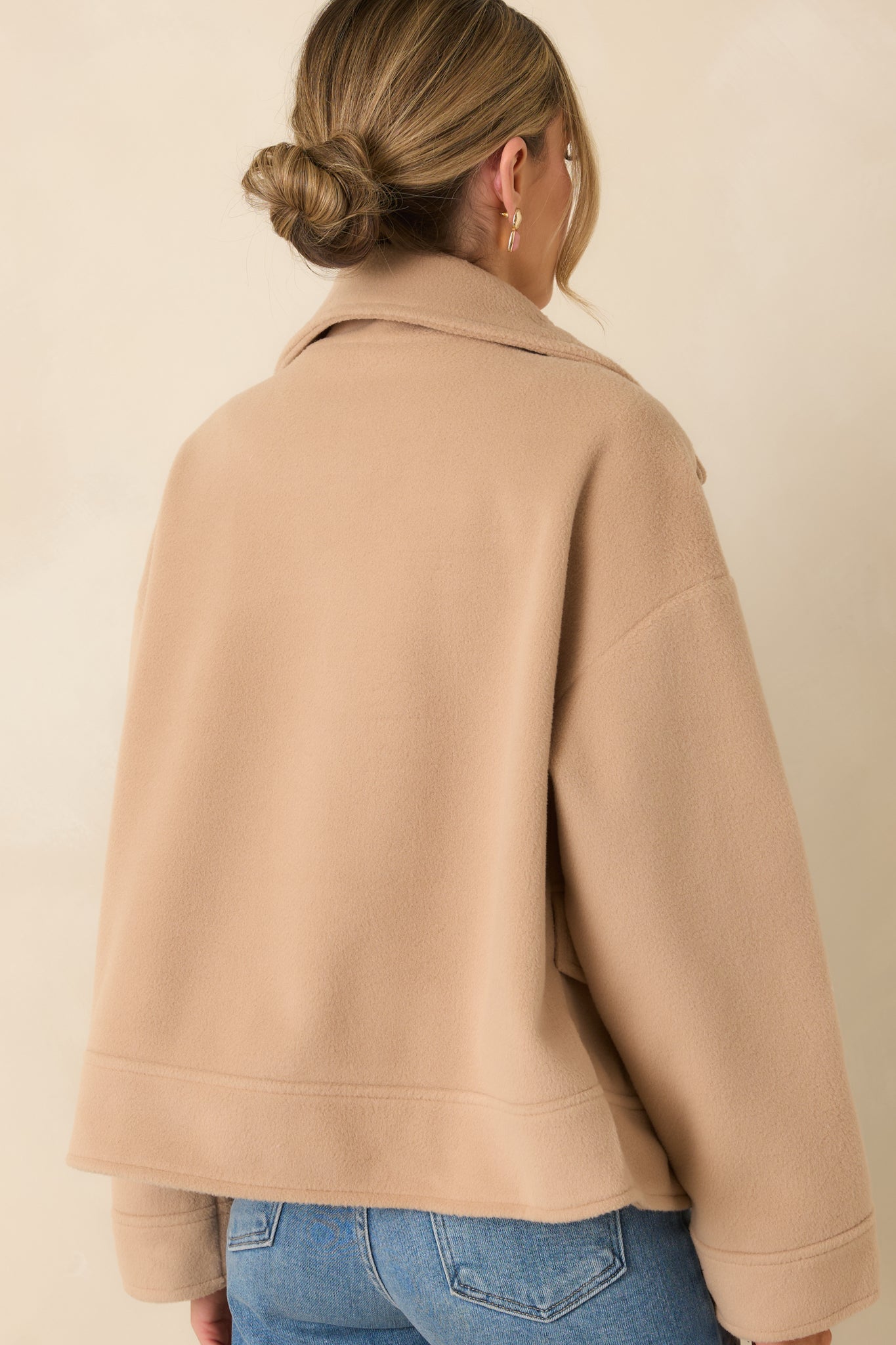 Rear view of taupe double-breasted jacket with a cropped hemline and smooth lined interior structure.