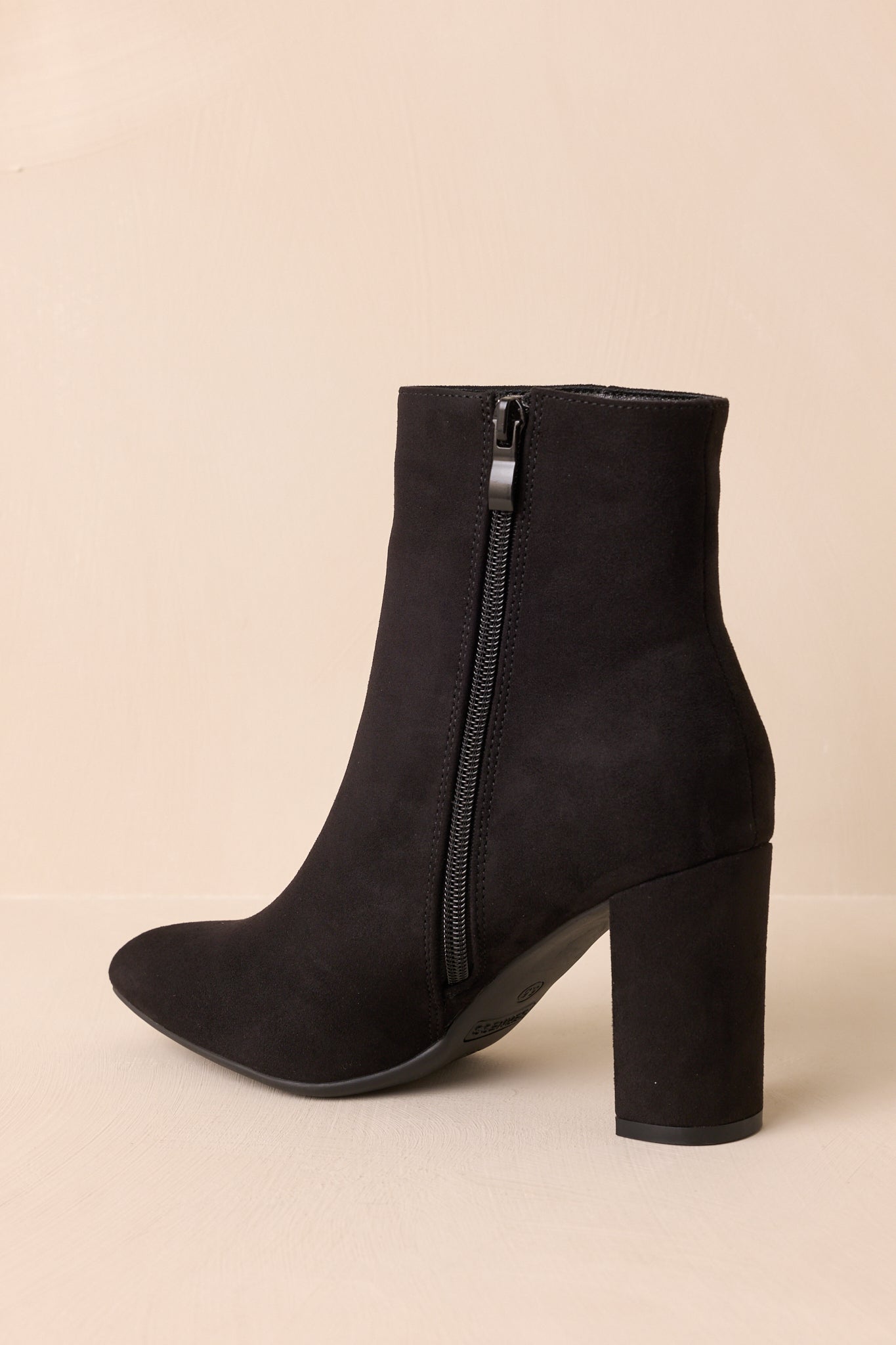Rear view of the black ankle boots showing the heel and sleek suede finish.