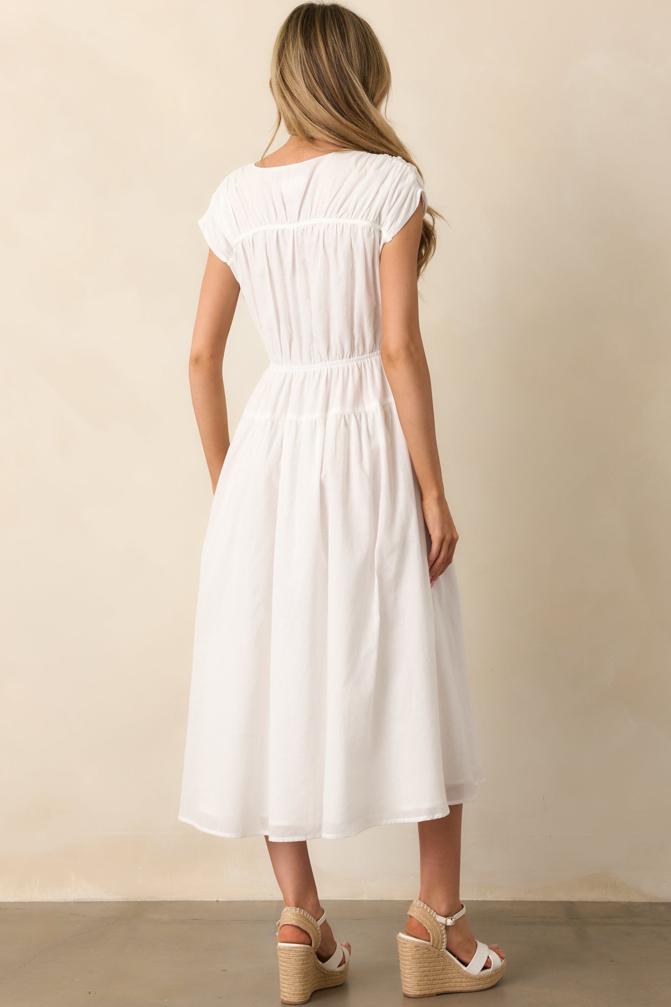 The rear view of the ivory dress highlights the clean design, with the elastic waist providing a secure fit, while the short cap sleeves and v-neckline add elegance to the silhouette.