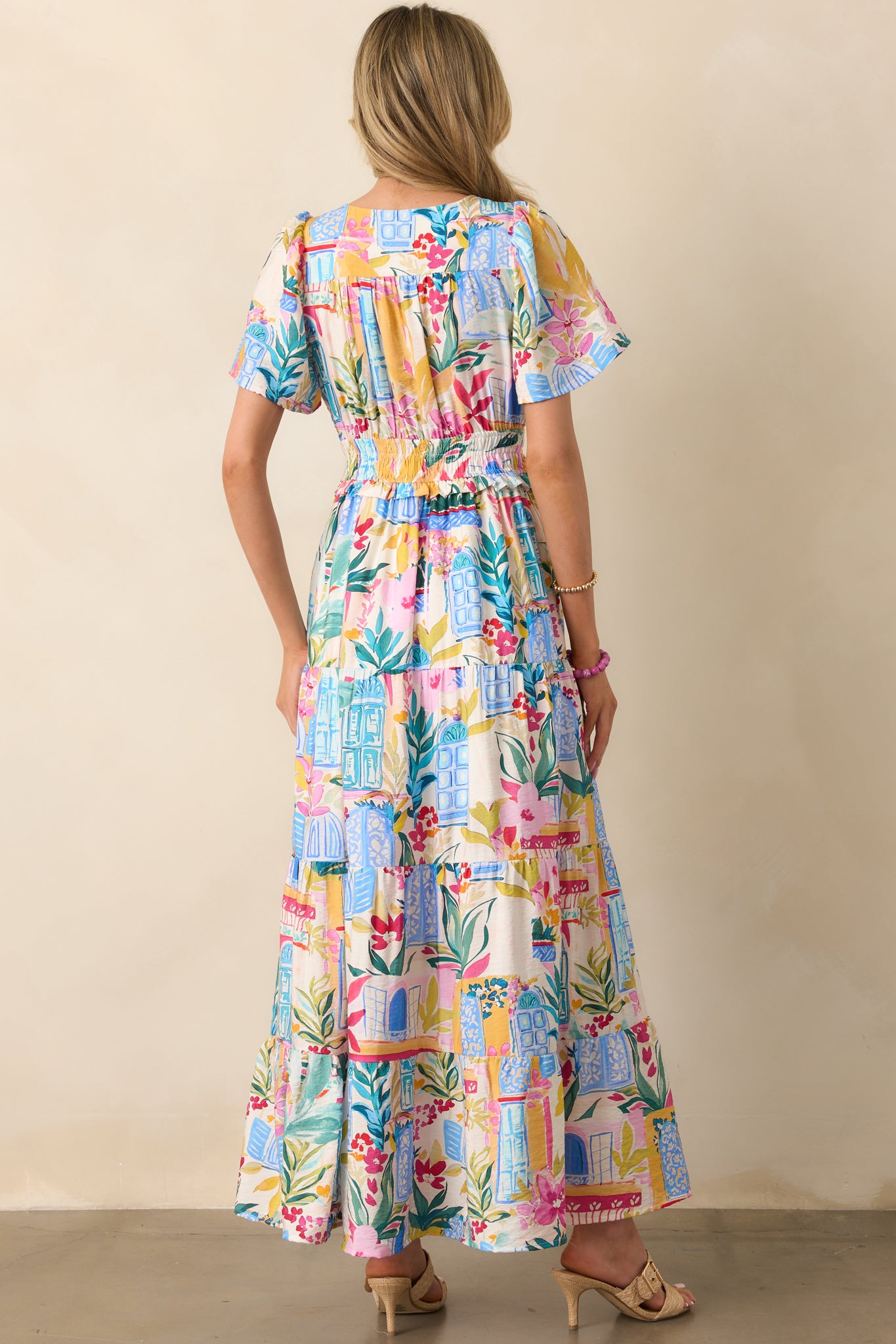 Rear view of the dress featuring the continued watercolor print, gathered skirt tiers, and gentle flare from the smocked waist down.