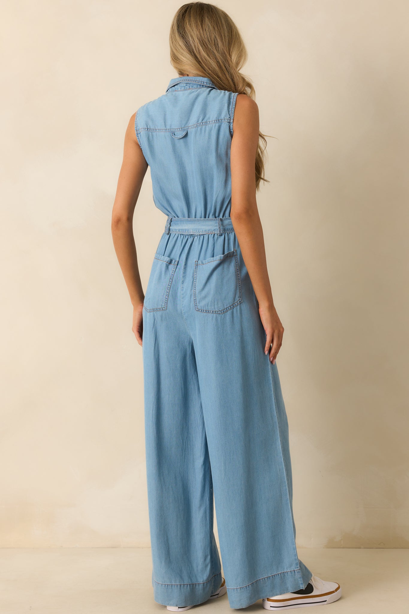 Rear view of the chambray jumpsuit highlighting the back elastic waist insert, wide-leg silhouette, and sleeveless design.