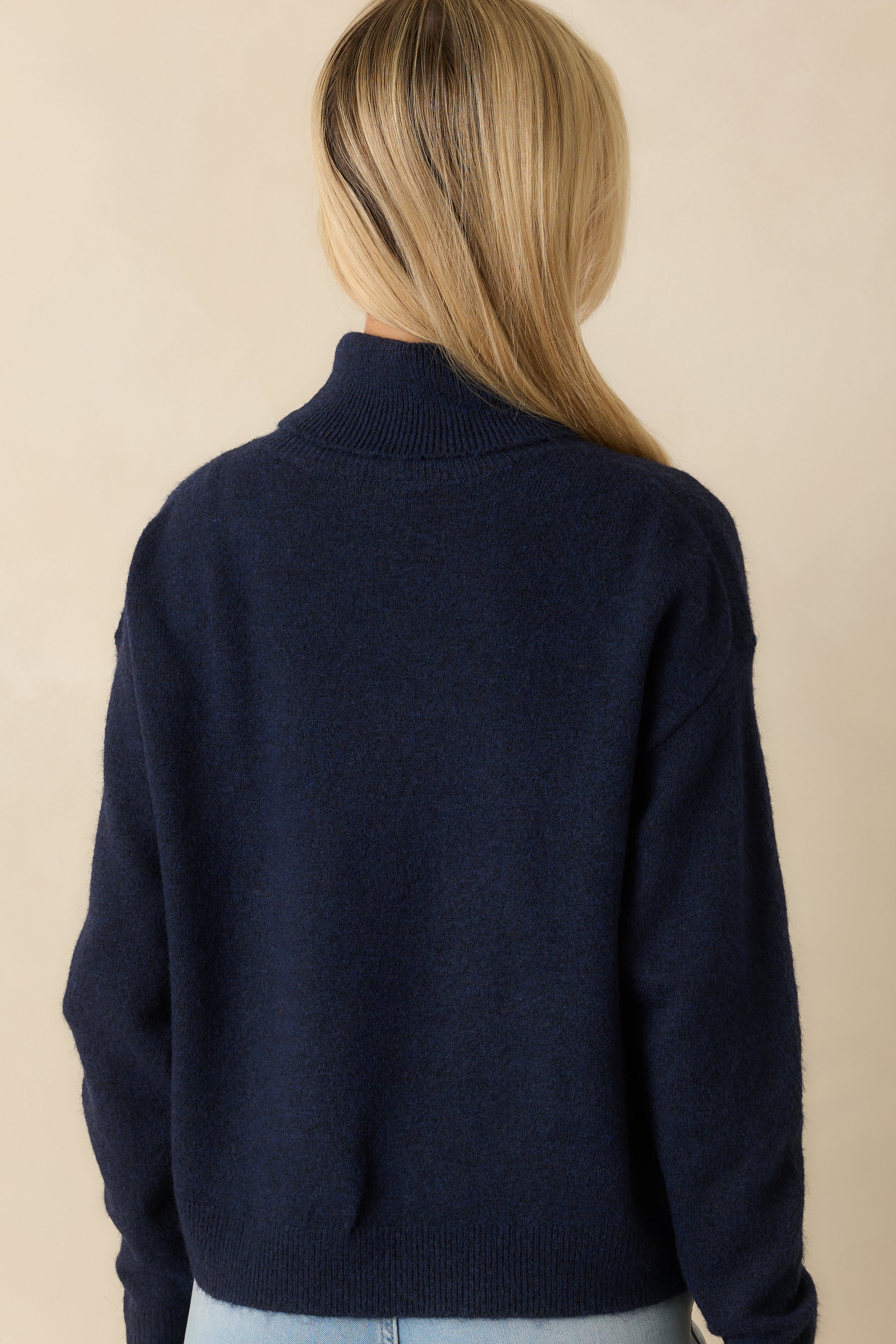 Rear view of navy sweater showing long sleeves, relaxed silhouette, and ribbed trim along hem and cuffs.