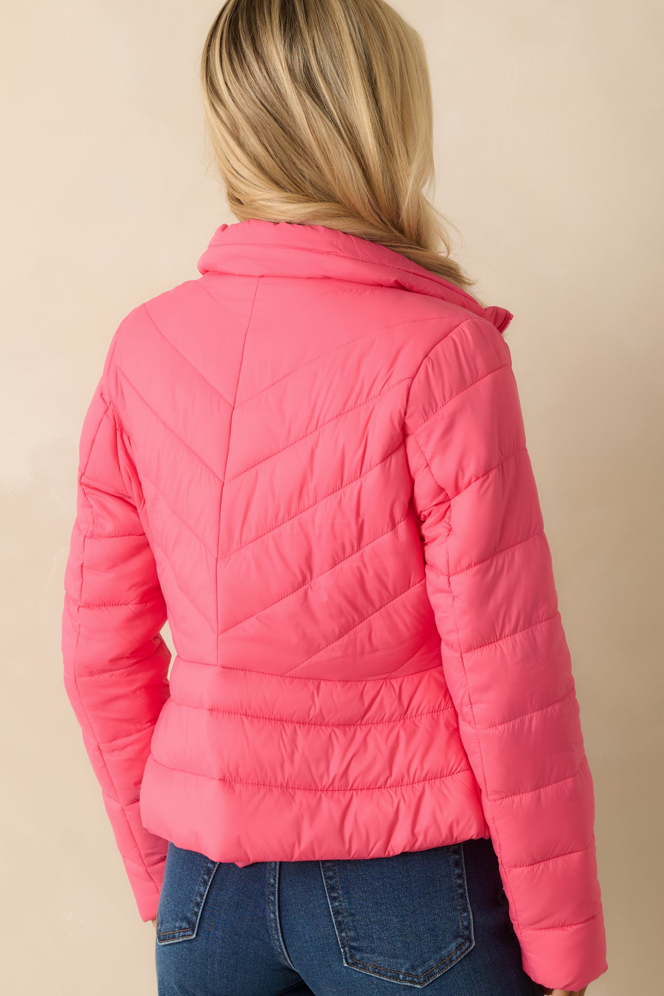 Rear view of the bright pink puffer jacket showing the diagonal quilted pattern and long sleeves.