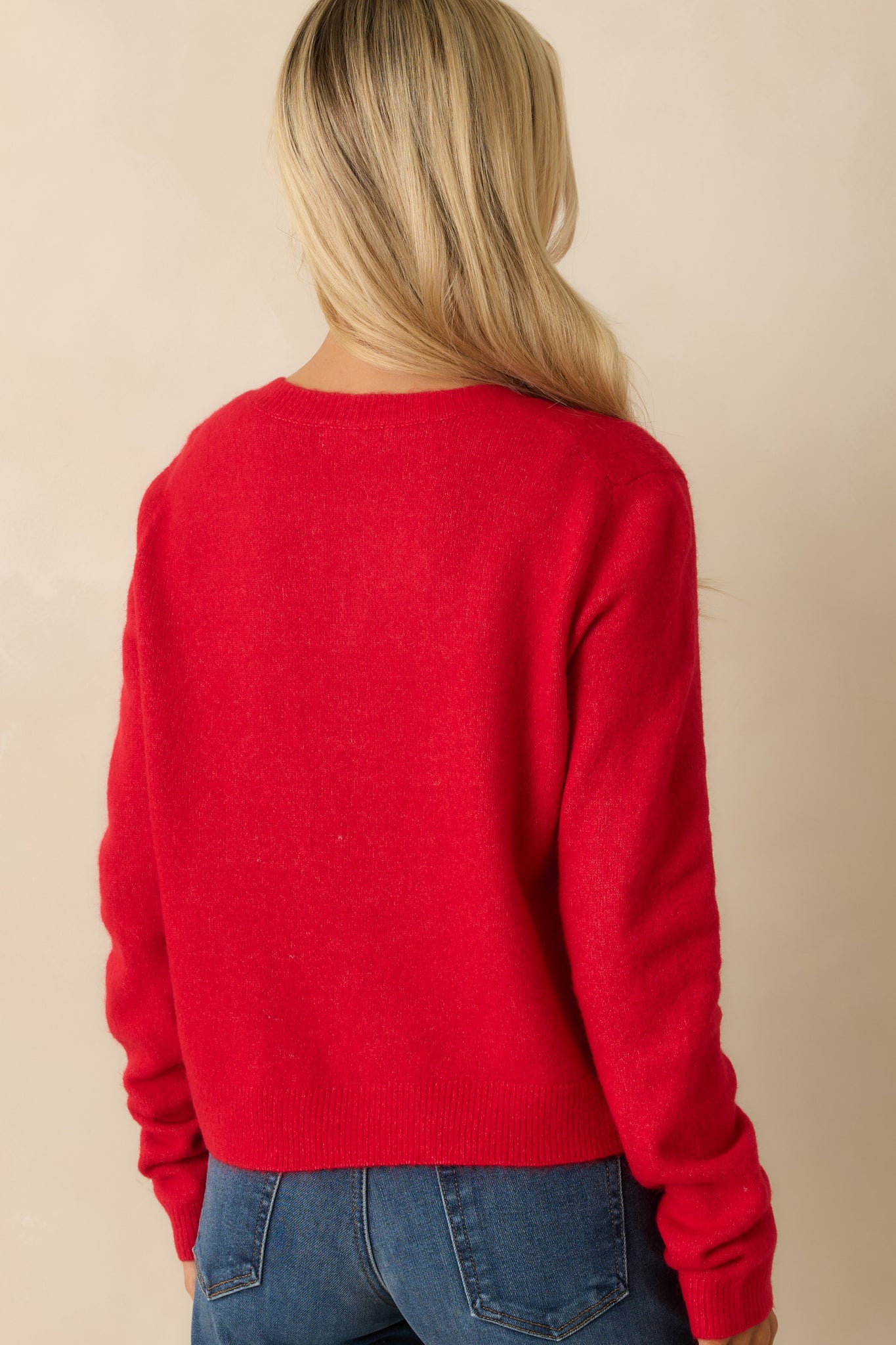 Rear view of red knit cardigan, showing relaxed fit, long sleeves, and smooth ribbed trim along hem and cuffs.