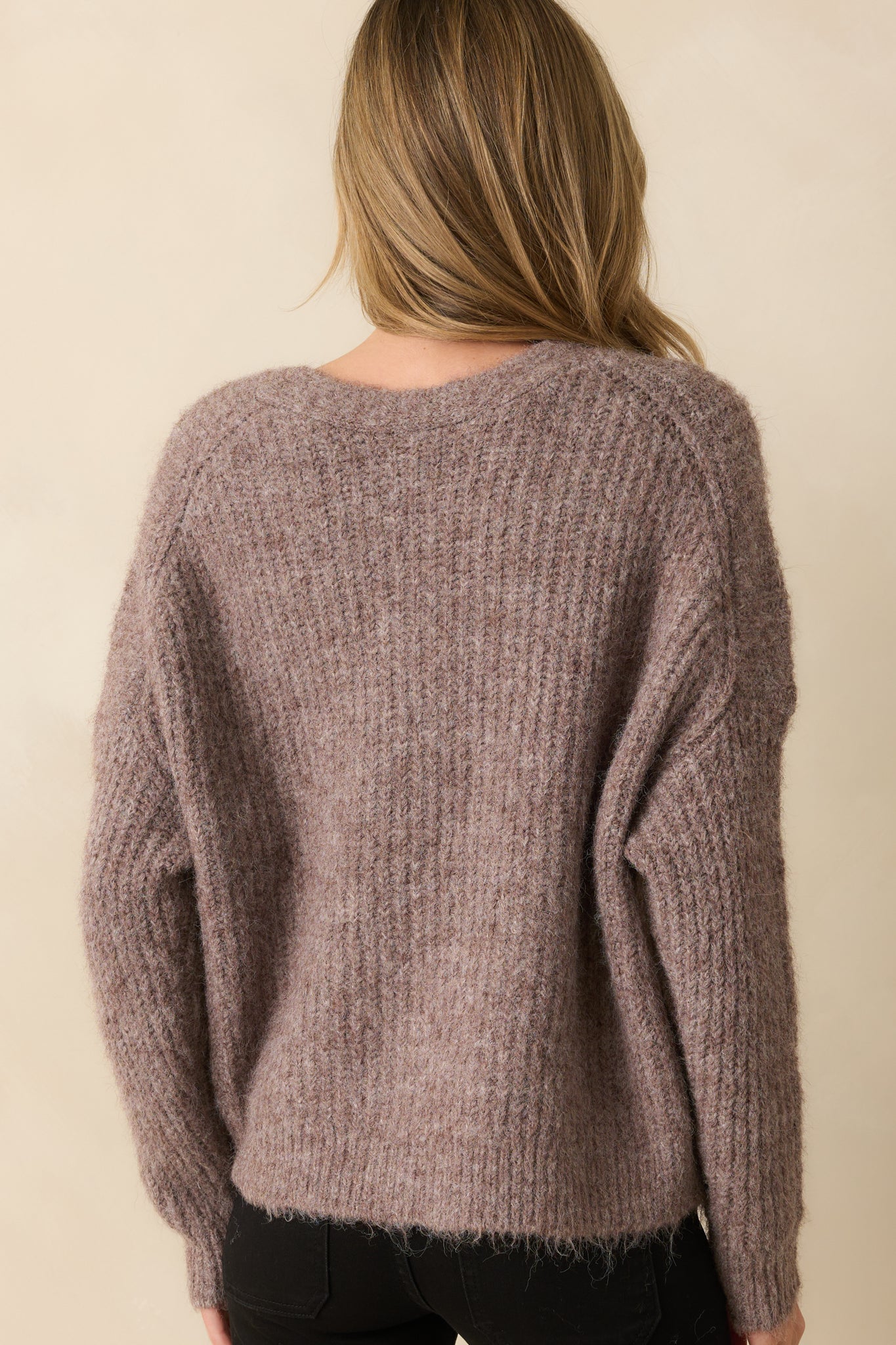 Rear view of the taupe cardigan showing long sleeves, ribbed knit texture, and relaxed silhouette.