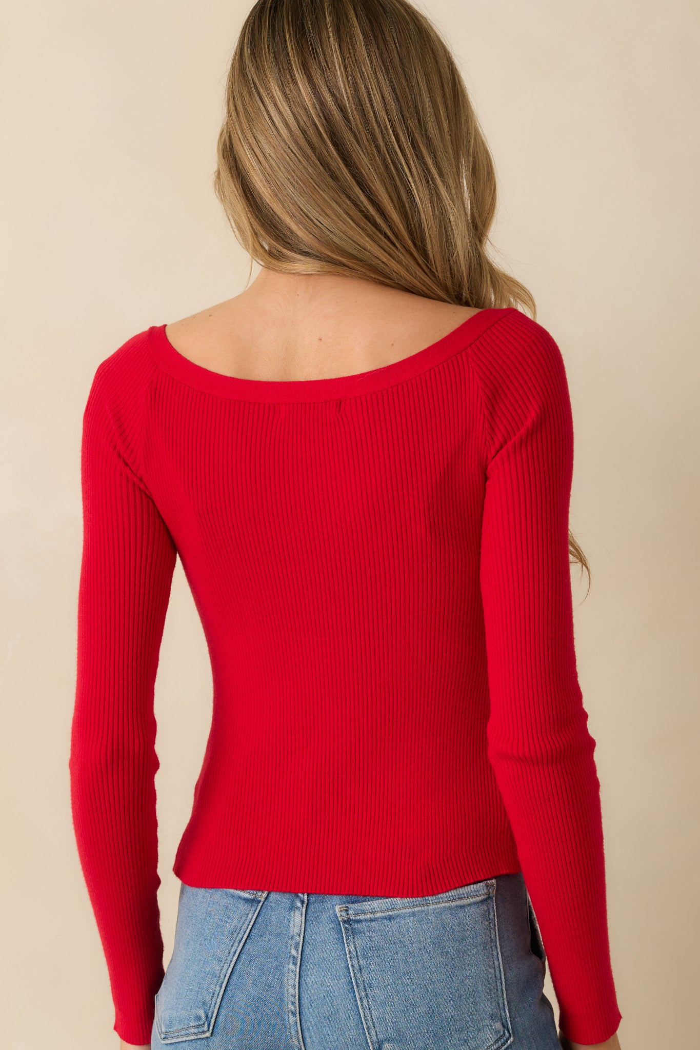 Rear view of red ribbed sweater, showing fitted cropped silhouette, long sleeves, and smooth knit finish.
