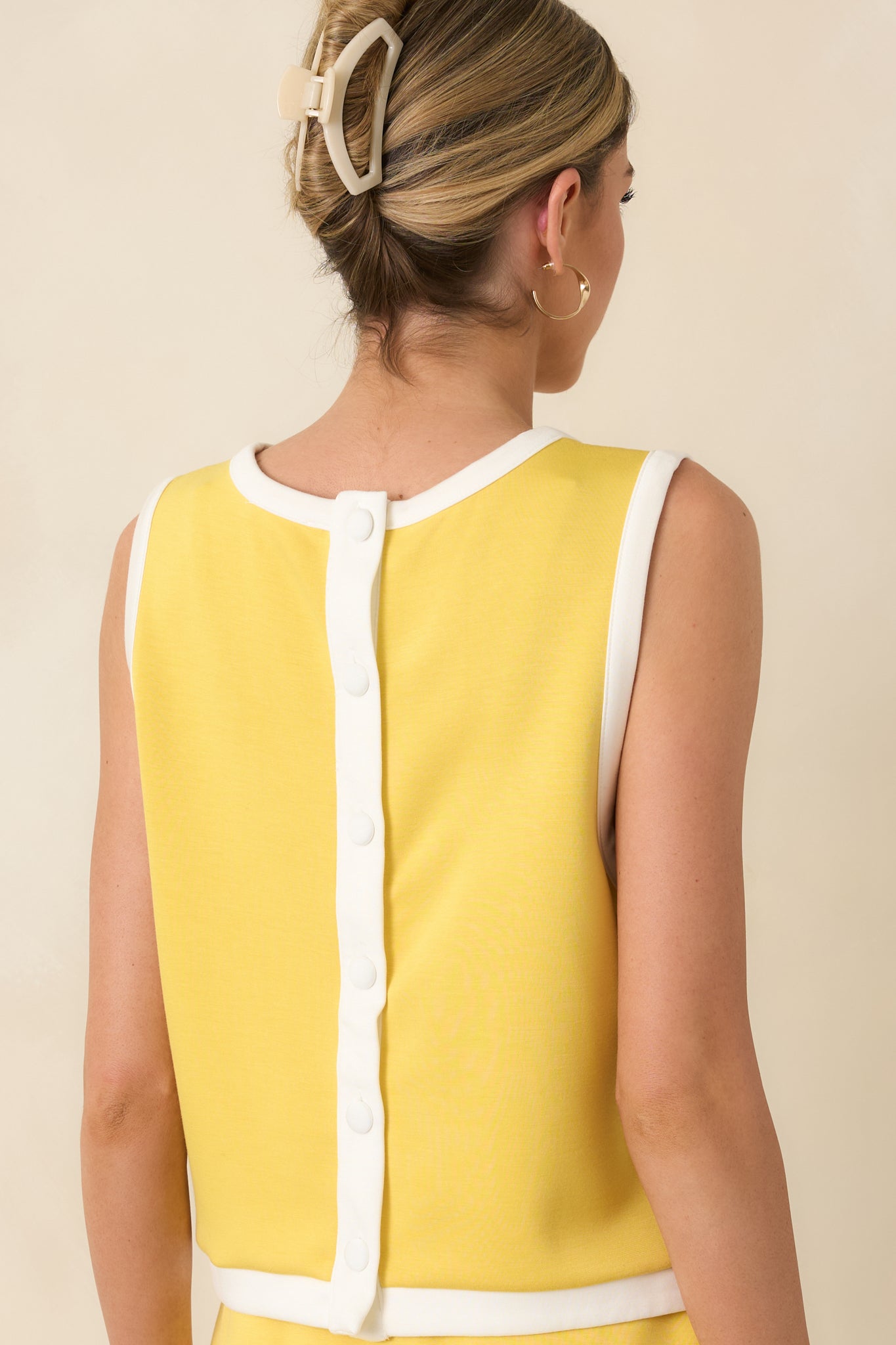 Rear view of the yellow top showing full button-back closure and subtle side slits.
