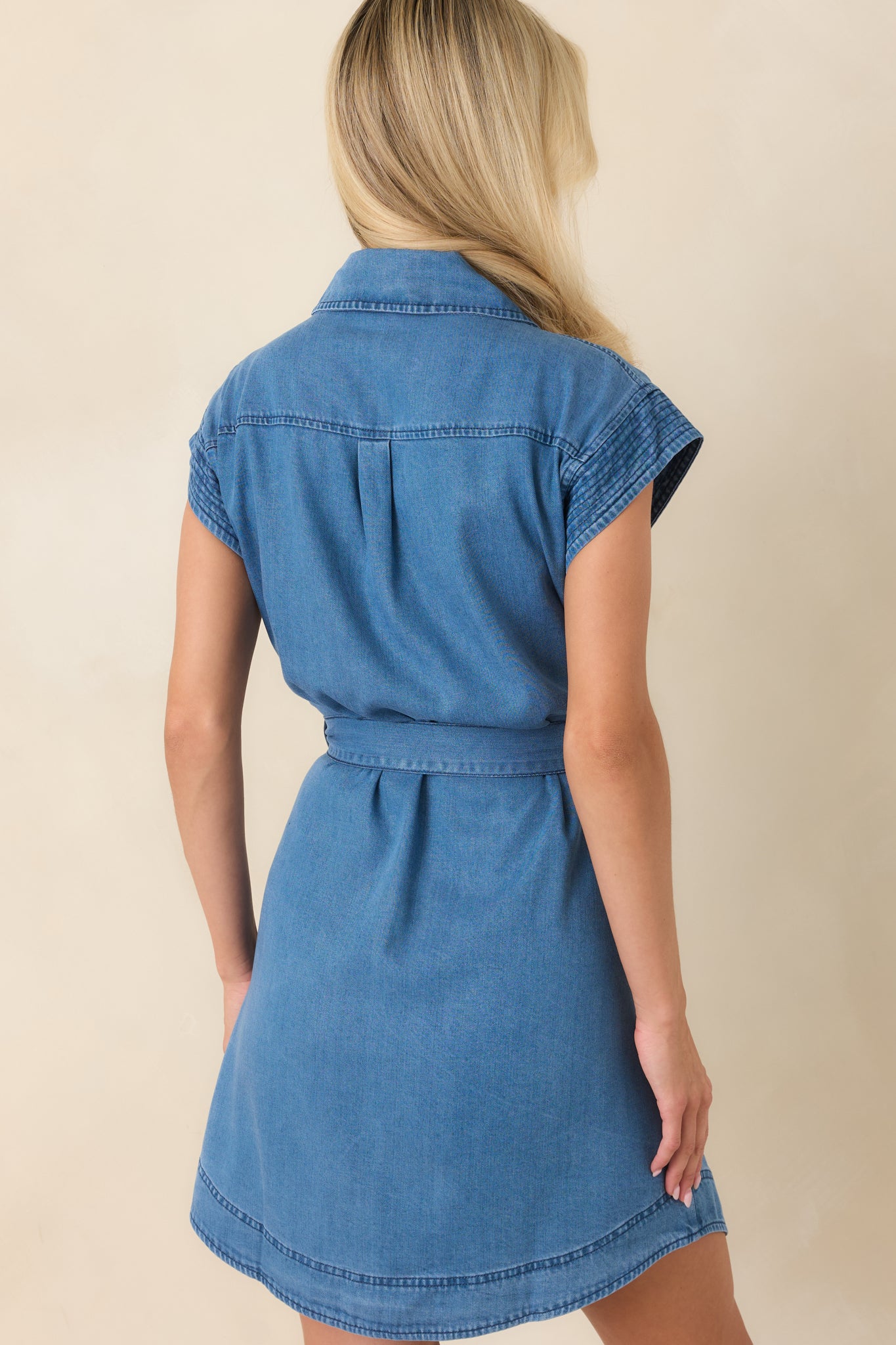 Rear view of the washed indigo mini dress featuring a softly curved hem and removable self-tie belt.