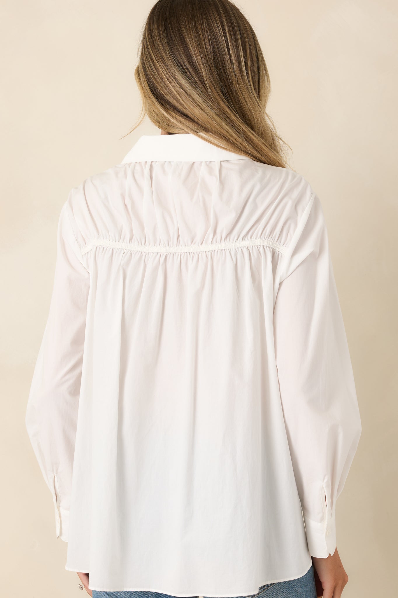 Rear view of the white button-up blouse highlighting the relaxed silhouette, smooth woven fabric, and clean back design.