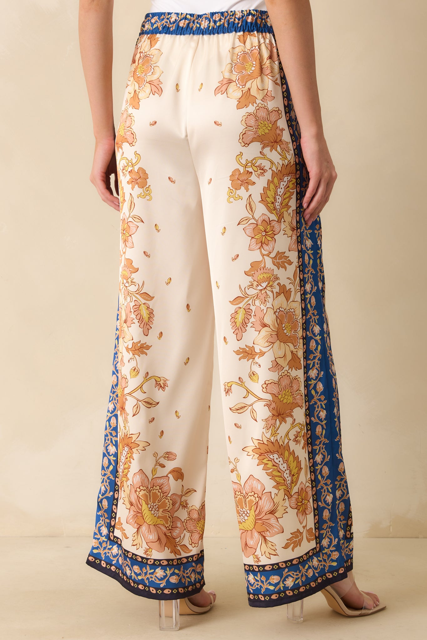 Rear view of the ivory pants showing high-rise waistband, wide-leg design, and floral print continuing across the back.