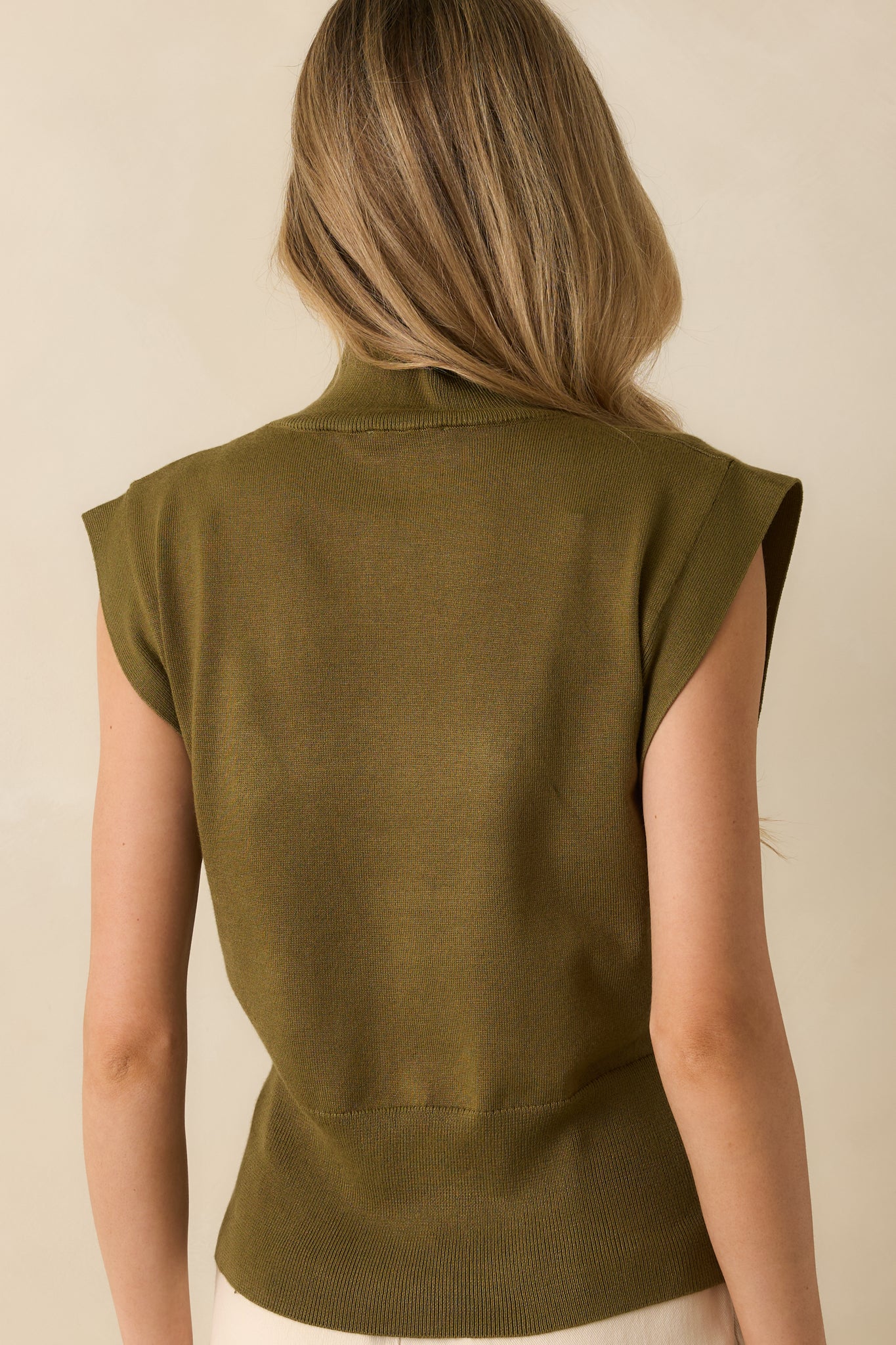 Rear view of olive green knit top showing cap sleeves, fitted waistband, and smooth knit fabric.