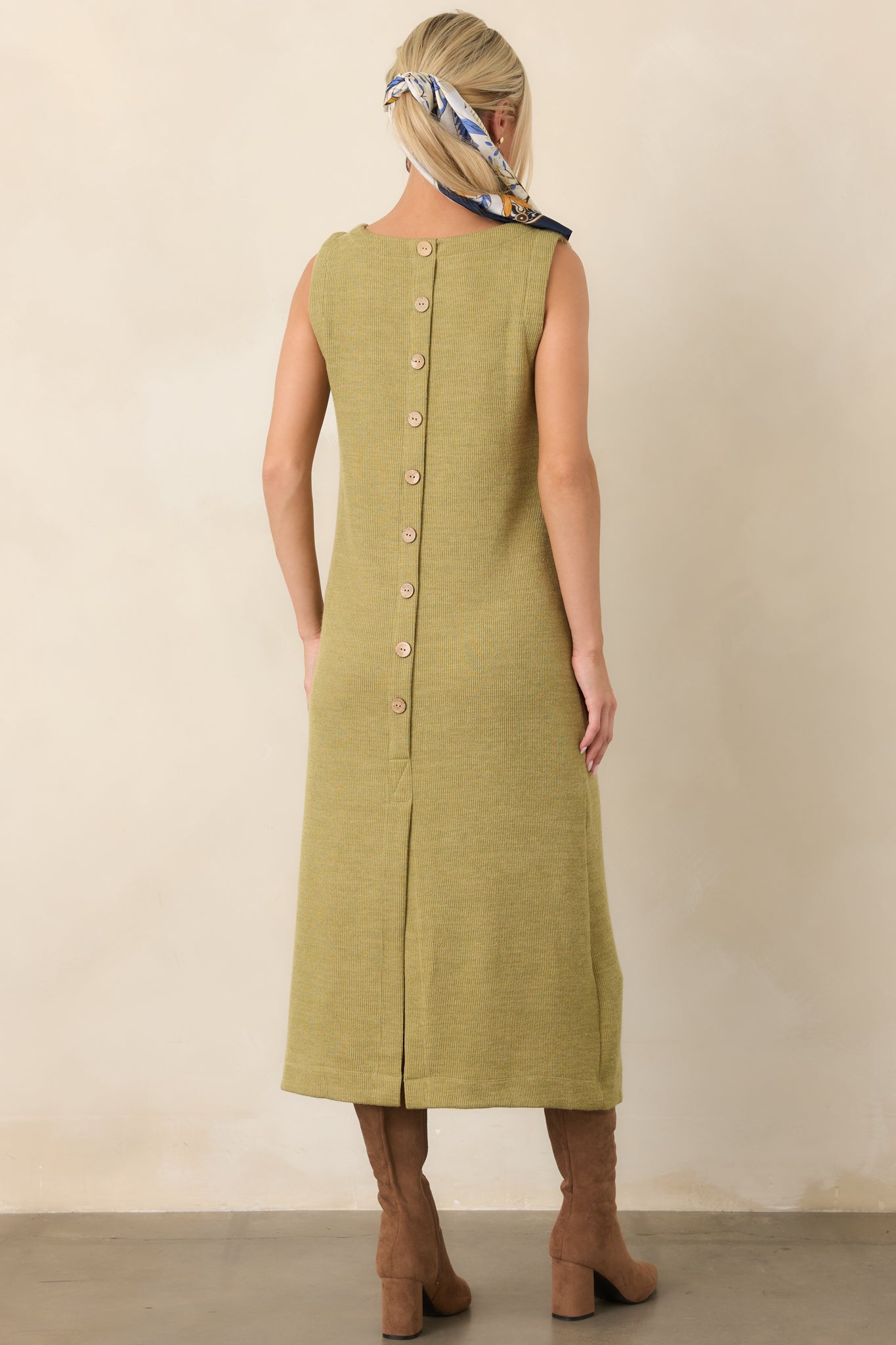 Rear view of the olive green rib knit midi dress showing the decorative button detail and back slit hem.