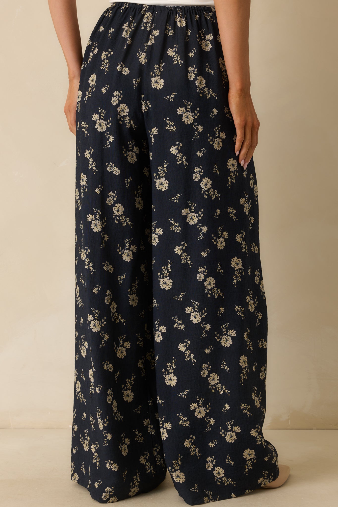 Rear view of the pants, showing the wide-leg cut, high-rise fit, and floral print details.