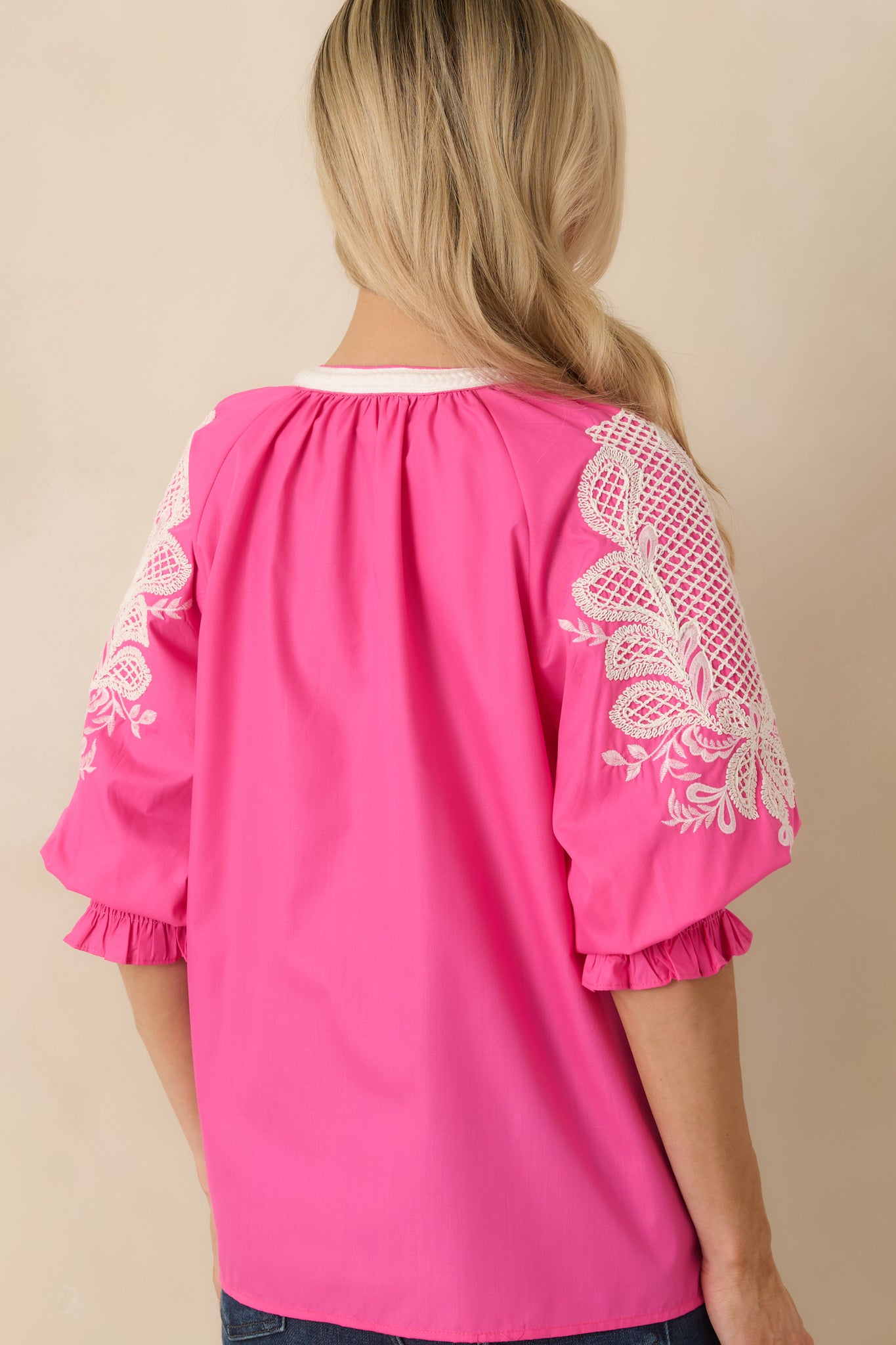 Rear view of the pink embroidered top showing consistent embroidery and a relaxed silhouette.

