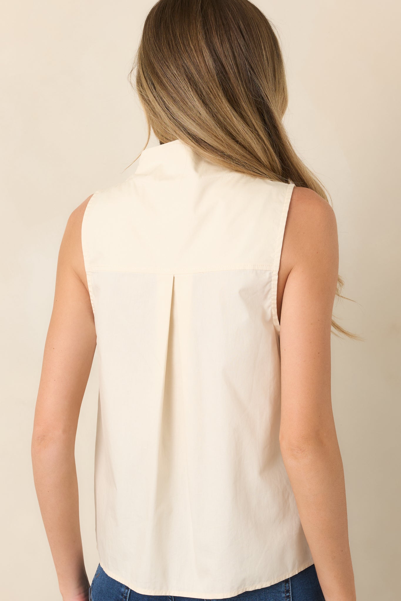 Rear view of the sleeveless cotton blouse showcasing the textured pintuck pleats, softly structured collar, and clean streamlined shape.