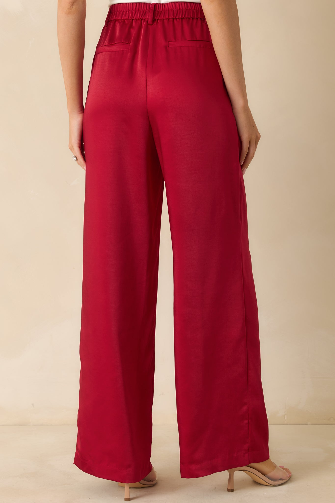 Rear view of the red high-waisted pants highlighting the faux back welt pockets and wide-leg fit.