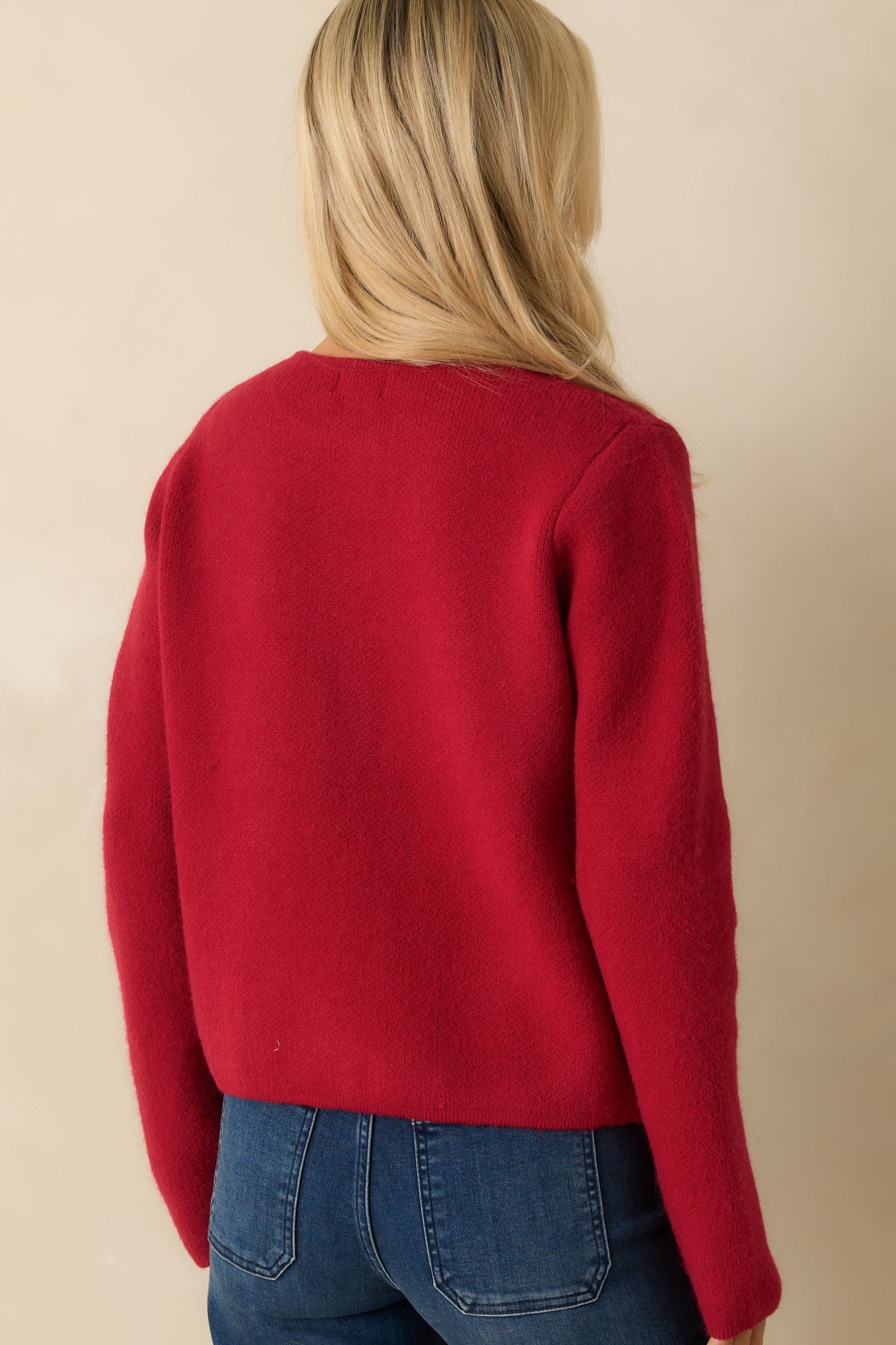 Rear view of the red knit cardigan highlighting the smooth knit finish and long-sleeve silhouette.