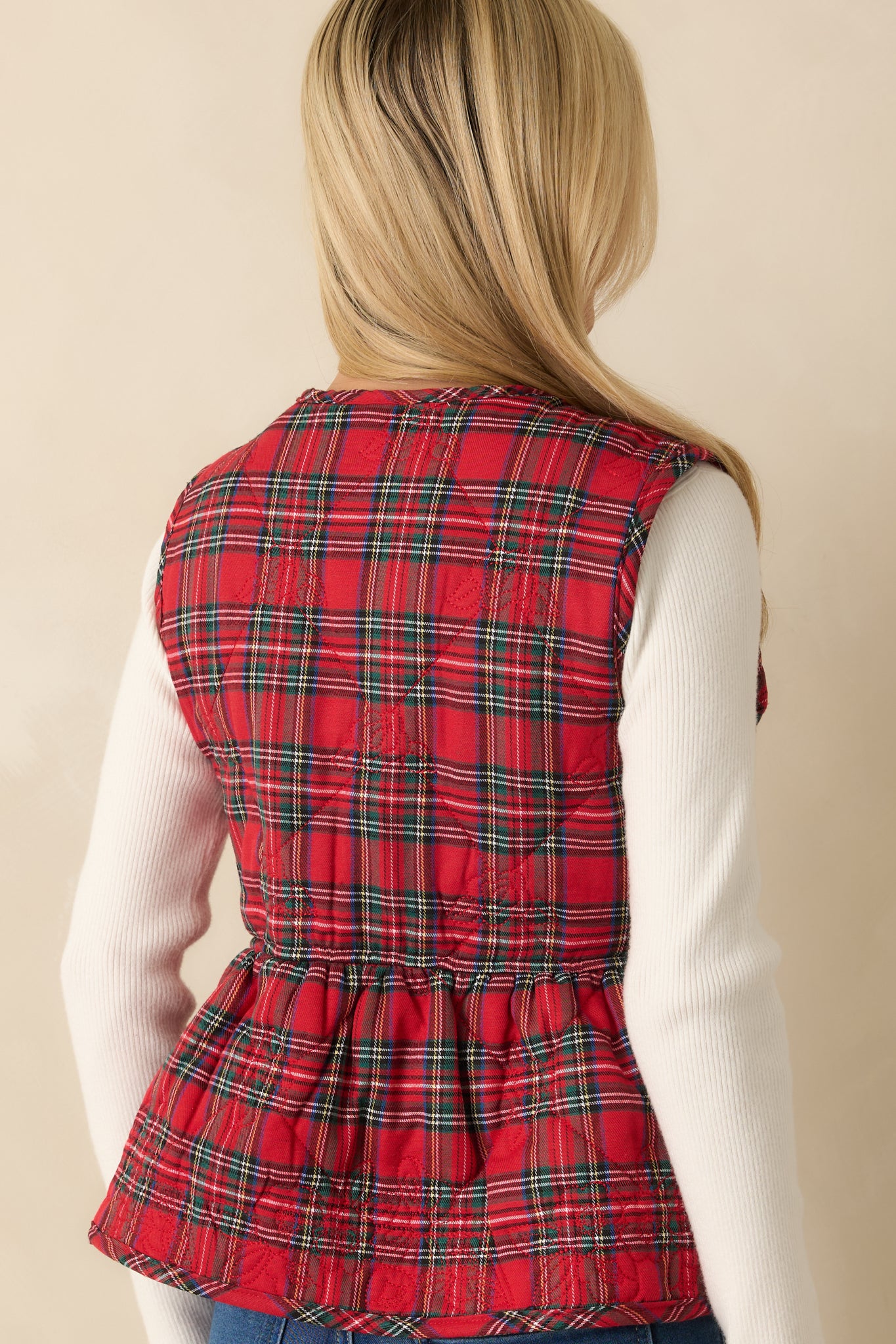 Rear view of the red plaid vest highlighting the quilted fabric and structured peplum-style hem.

