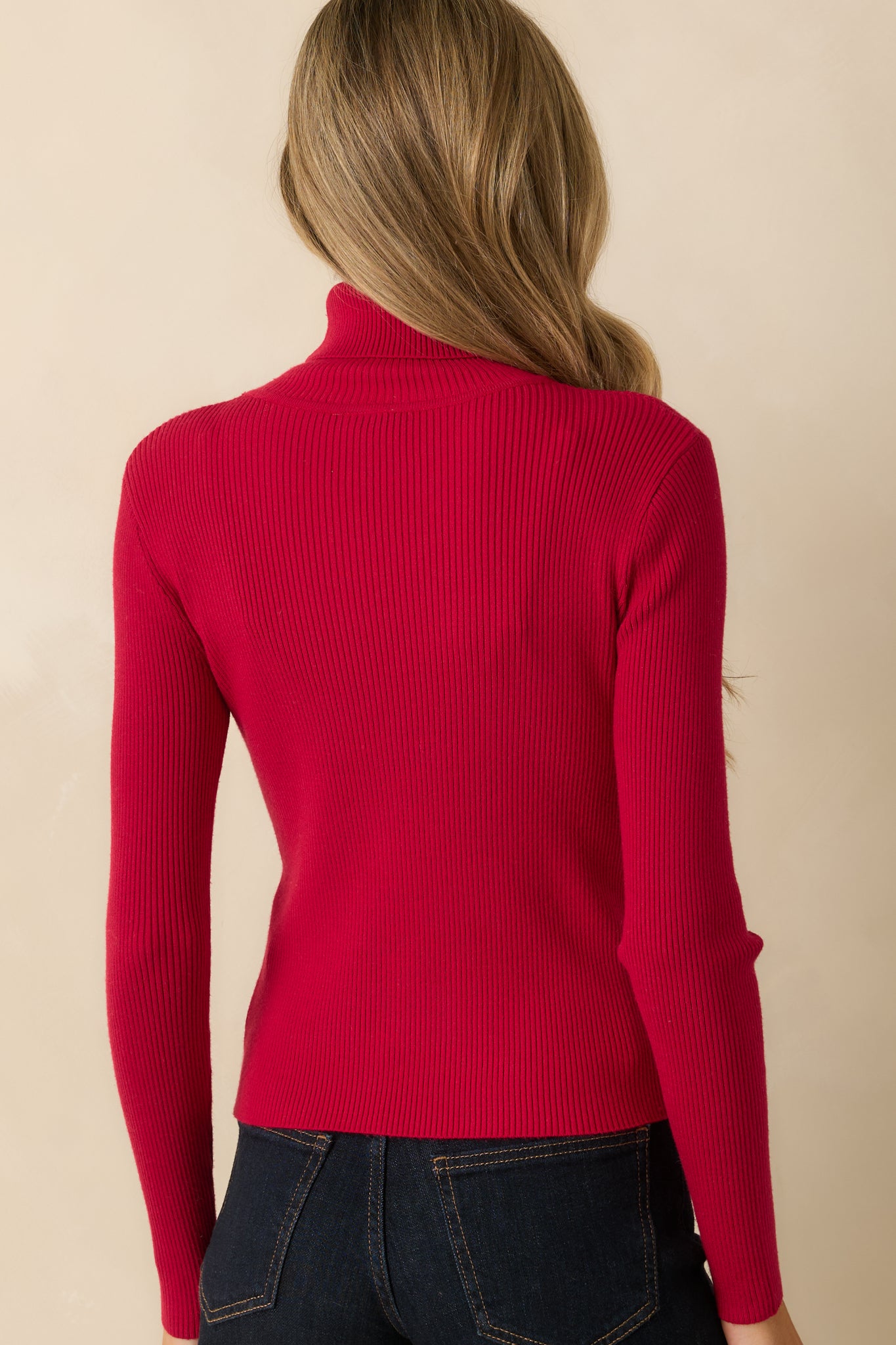 Rear view of red ribbed knit sweater showing fitted silhouette, long sleeves, and straight hem.