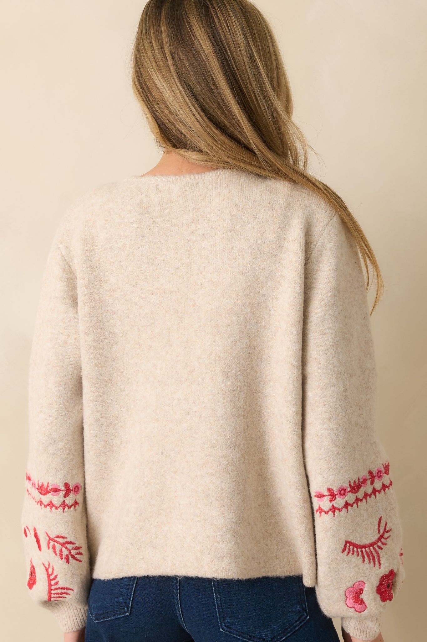 Rear view showing the relaxed fit and floral embroidery along the back of the sleeves of the cardigan.