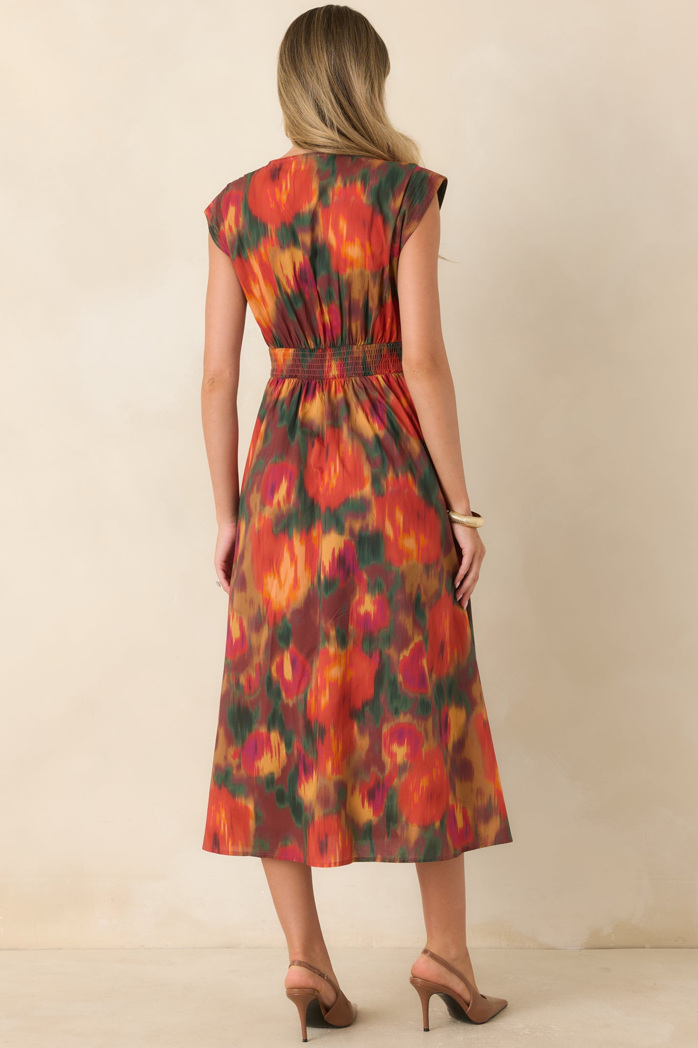 Rear view of the rust floral midi dress featuring the colorful painterly print, fitted bodice, smocked back waist, and full gathered skirt.