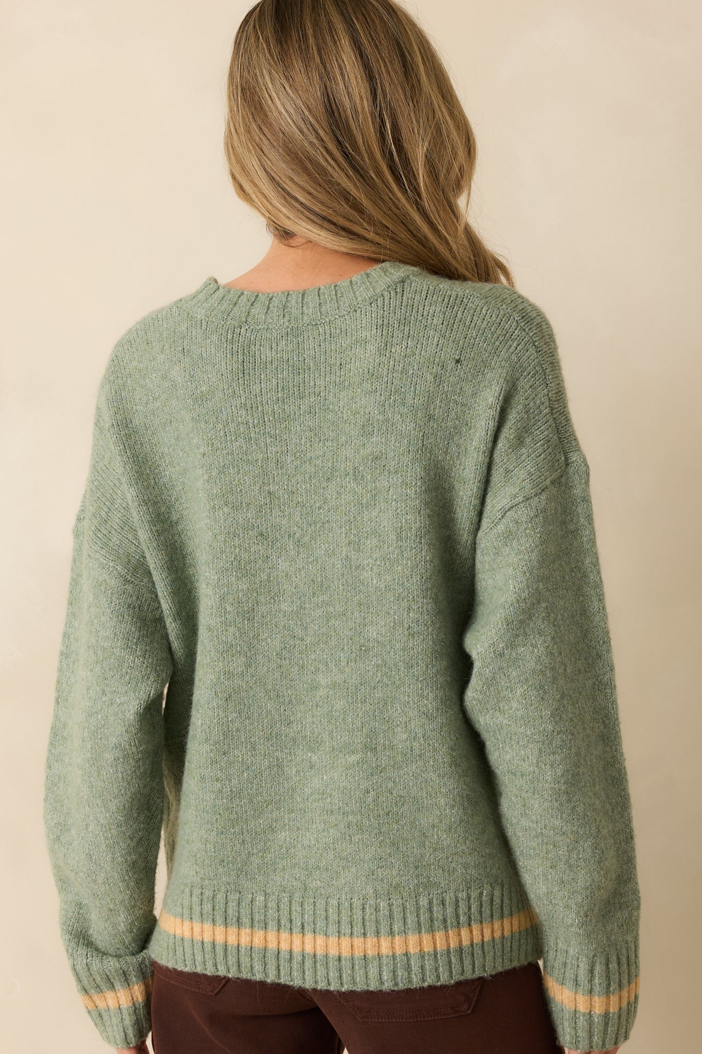Rear view of the sage green pullover displaying the smooth knit back and long sleeves.