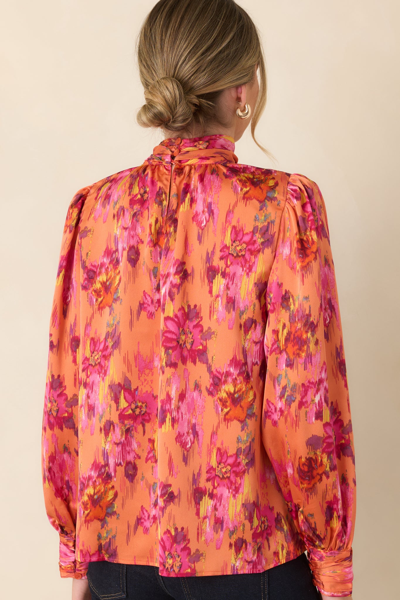 Rear view of the satin top featuring its smooth drape, lightly gathered shoulders, long balloon sleeves, and polished silhouette.