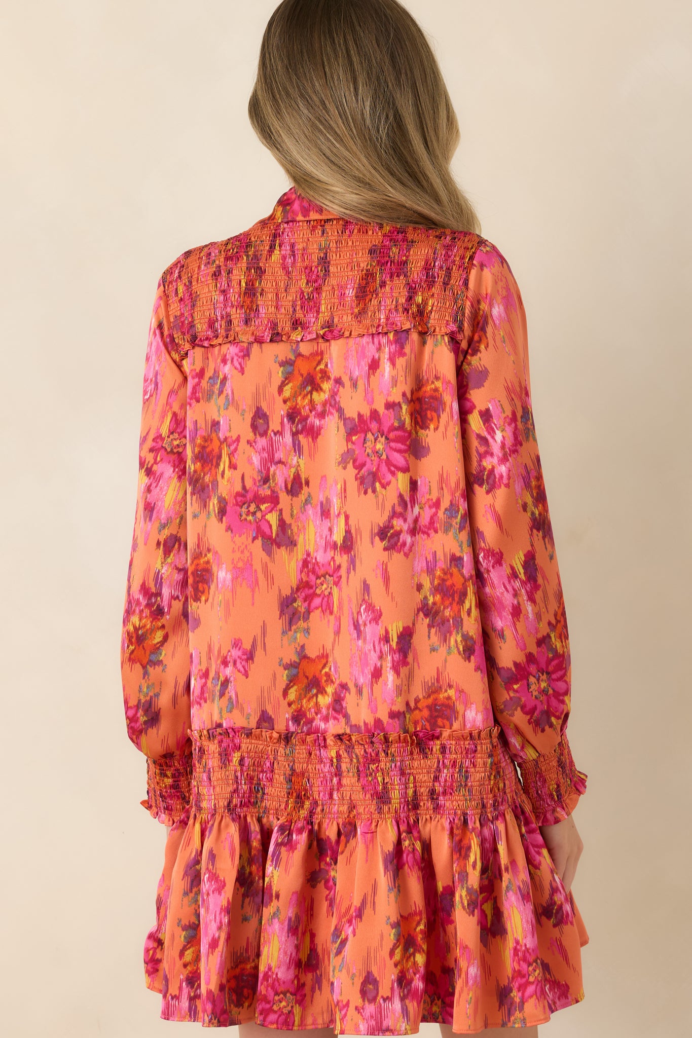 Rear view of the satin mini dress showcasing the relaxed drop-waist silhouette, long balloon sleeves, smocked cuffs, and flouncy skirt.