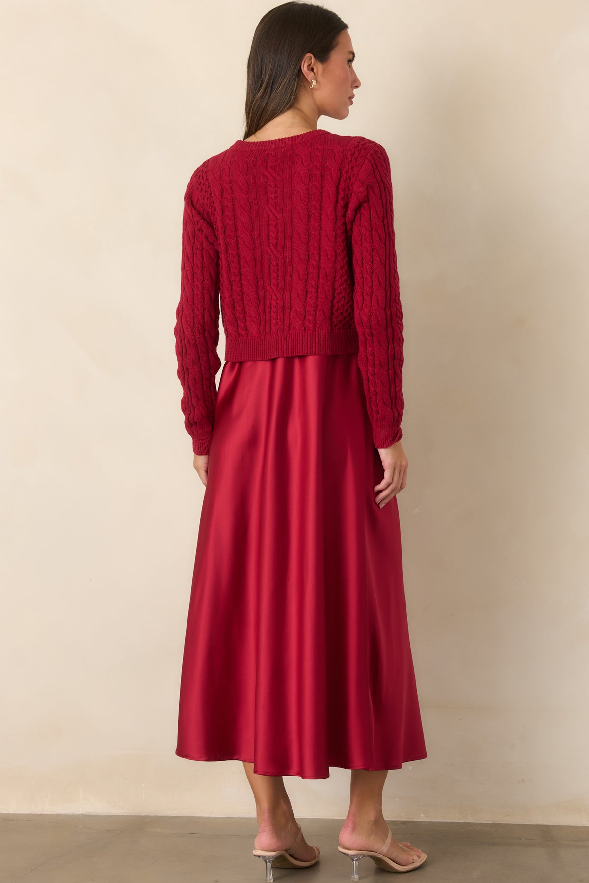 Rear view of the satin maxi dress layered beneath the cropped cable-knit cotton sweater.