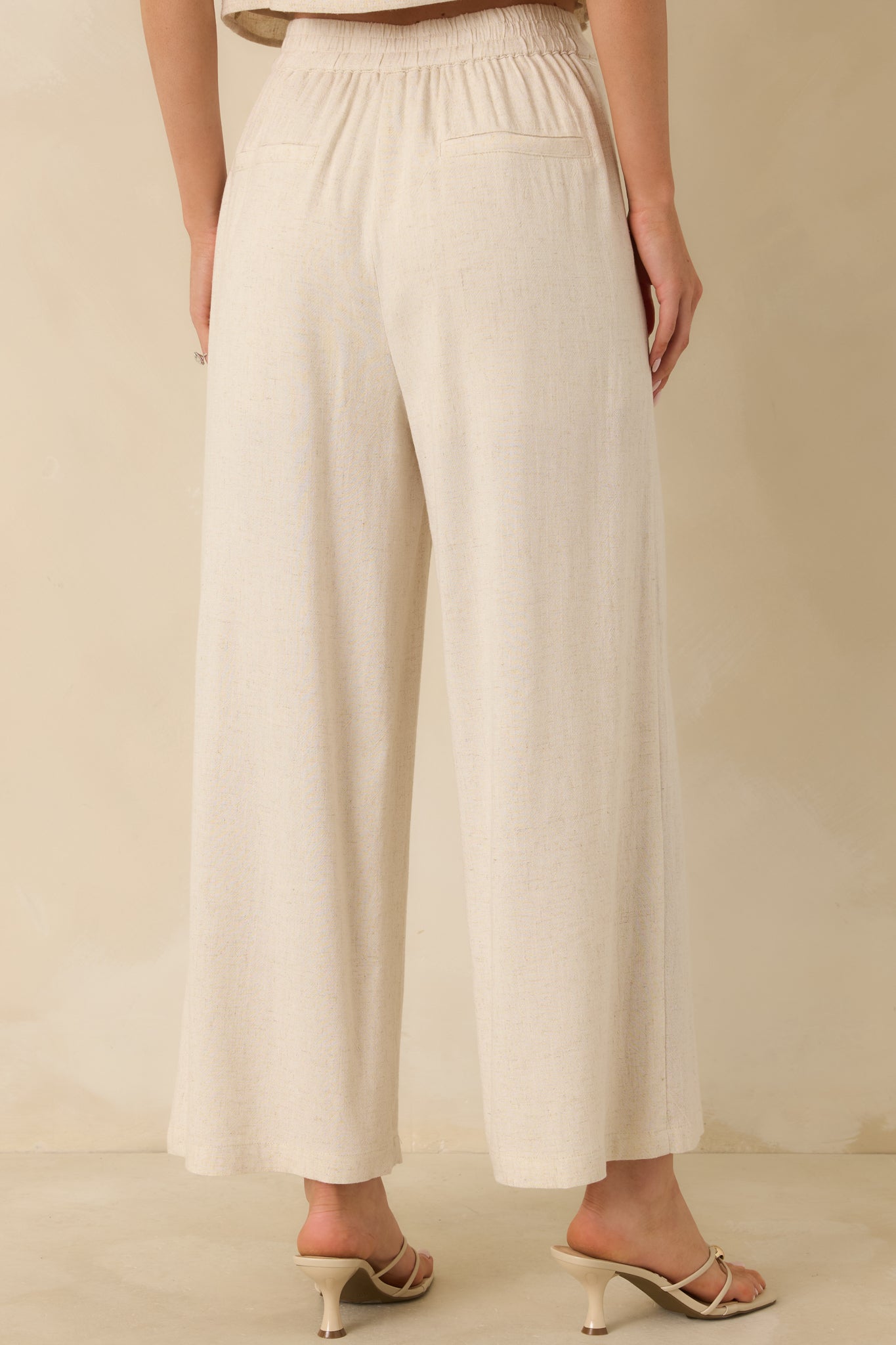 Rear view of the wide-leg pants showing patch pockets, high-rise fit, and flowing linen-blend fabric.
