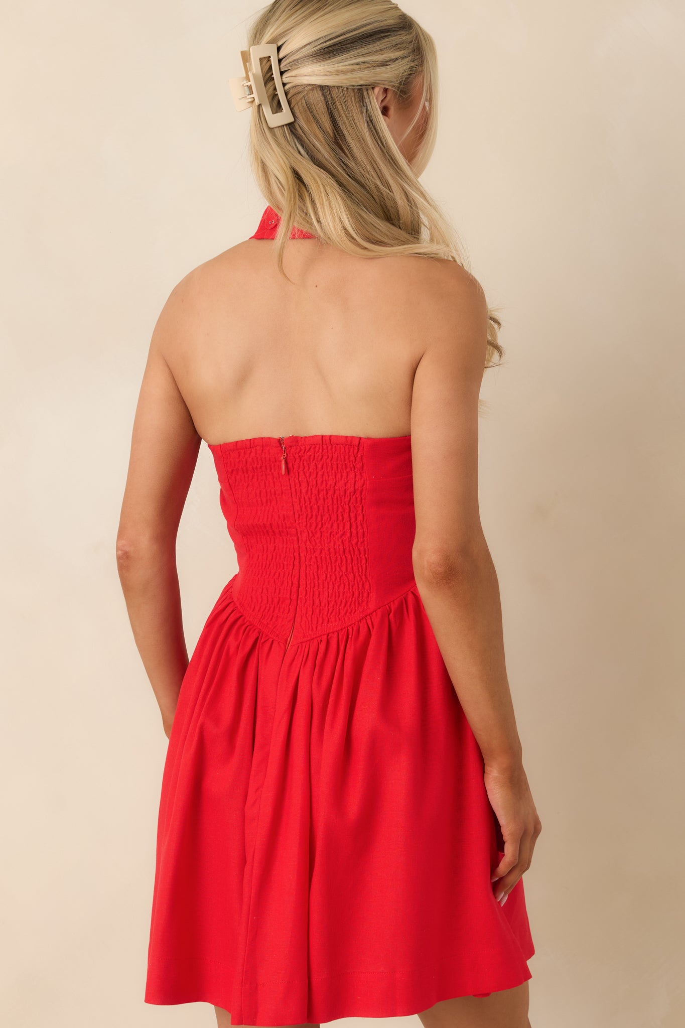 Rear view of red mini dress showing smocked elastic back and mini-length hem for stretch and ease.
