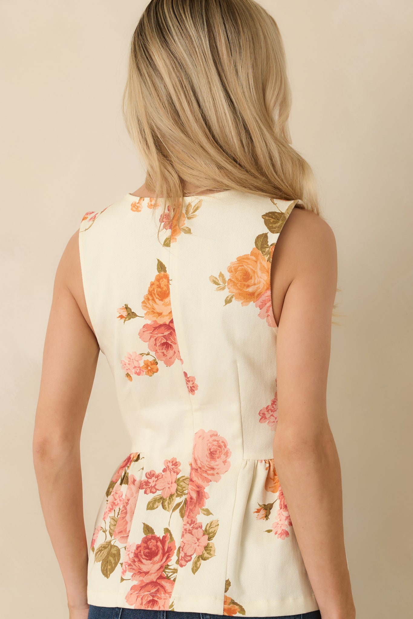 Rear view of the pink floral peplum top showing the back zipper closure and flared hem falling from the fitted waist.