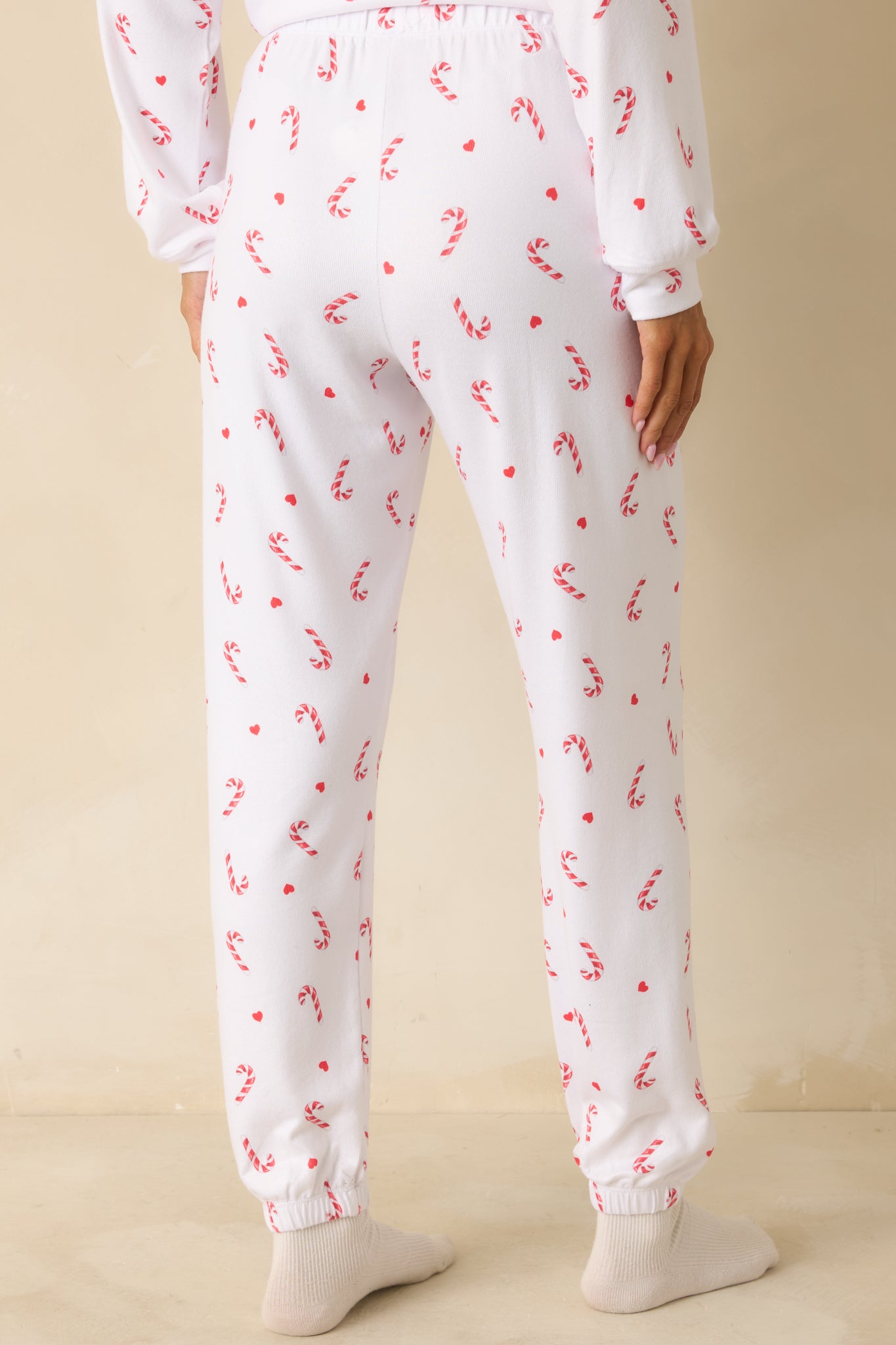 Rear view of white knit pajama pants, showing relaxed fit, elastic waistband, full-length silhouette, and cuffed hems.