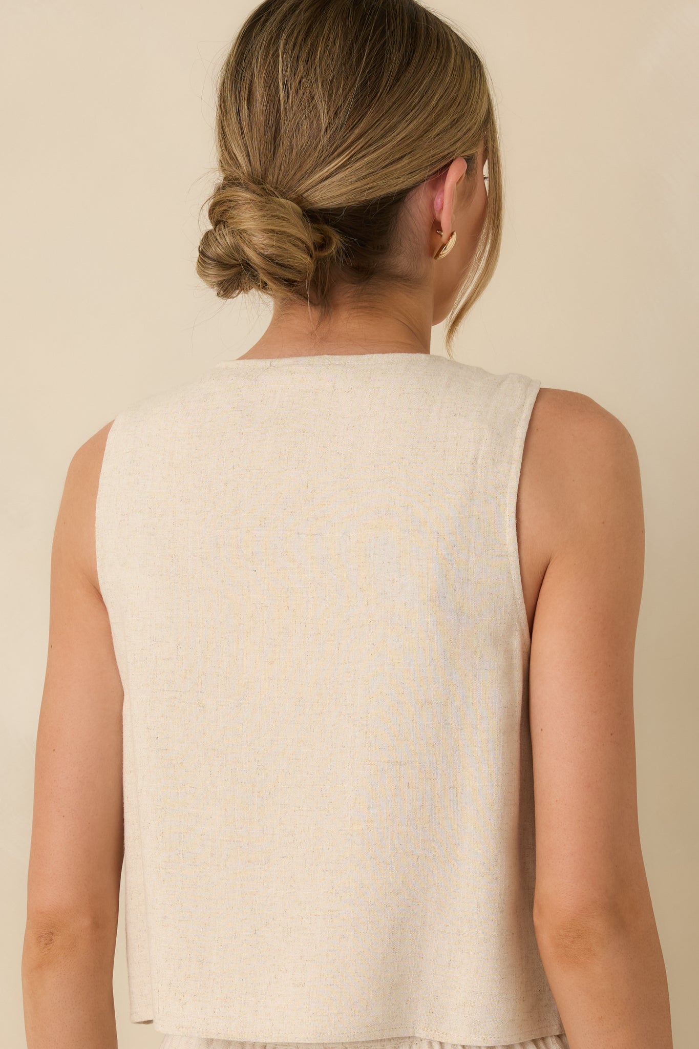 Rear view of the natural sleeveless button-up top showing the relaxed fit and soft linen-blend drape.