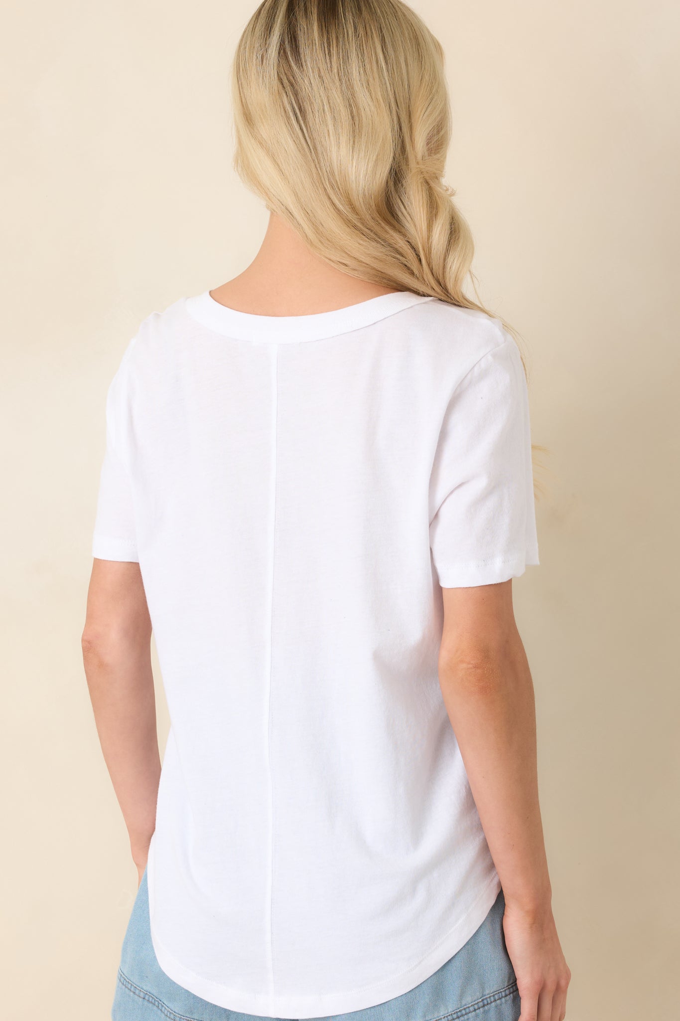 Rear view of the white top showing the relaxed silhouette, short sleeves, and smooth knit fabric for a classic fit.