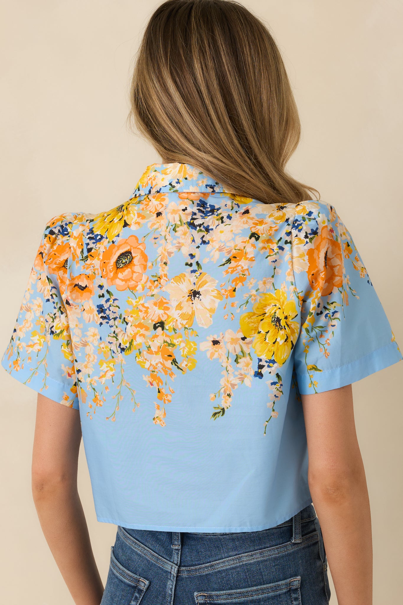 Rear view of the blue cotton floral top showing the relaxed silhouette, short sleeves, and continuous multicolor print.