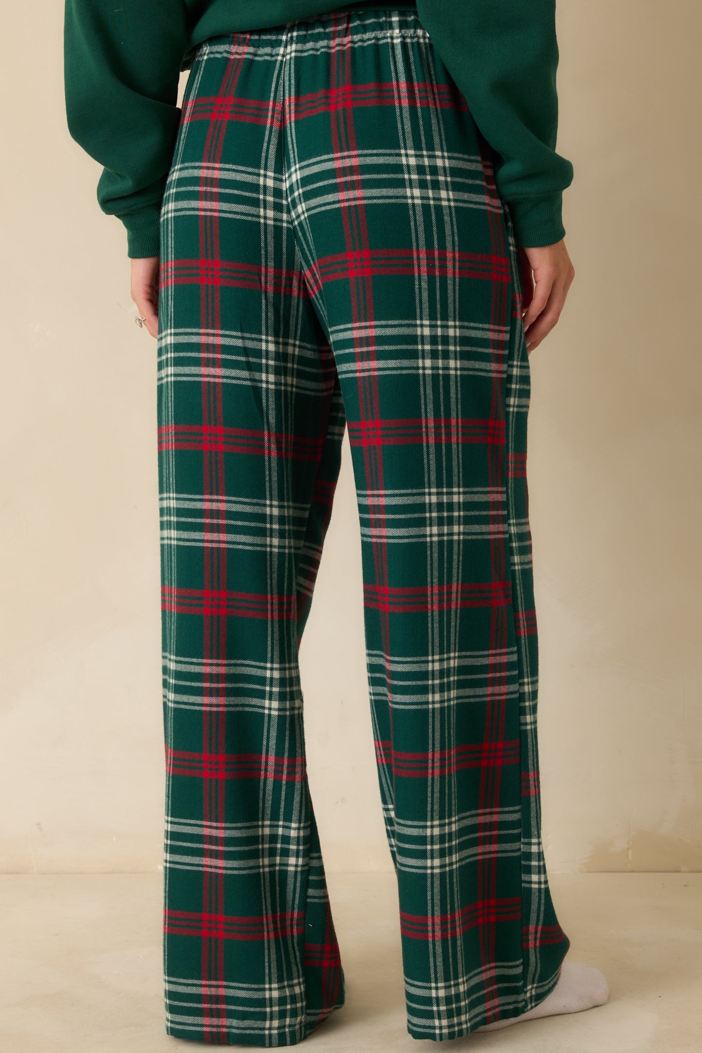 Rear view of green plaid pajama pants, showing straight-leg silhouette, elastic waistband, and smooth flannel finish.
